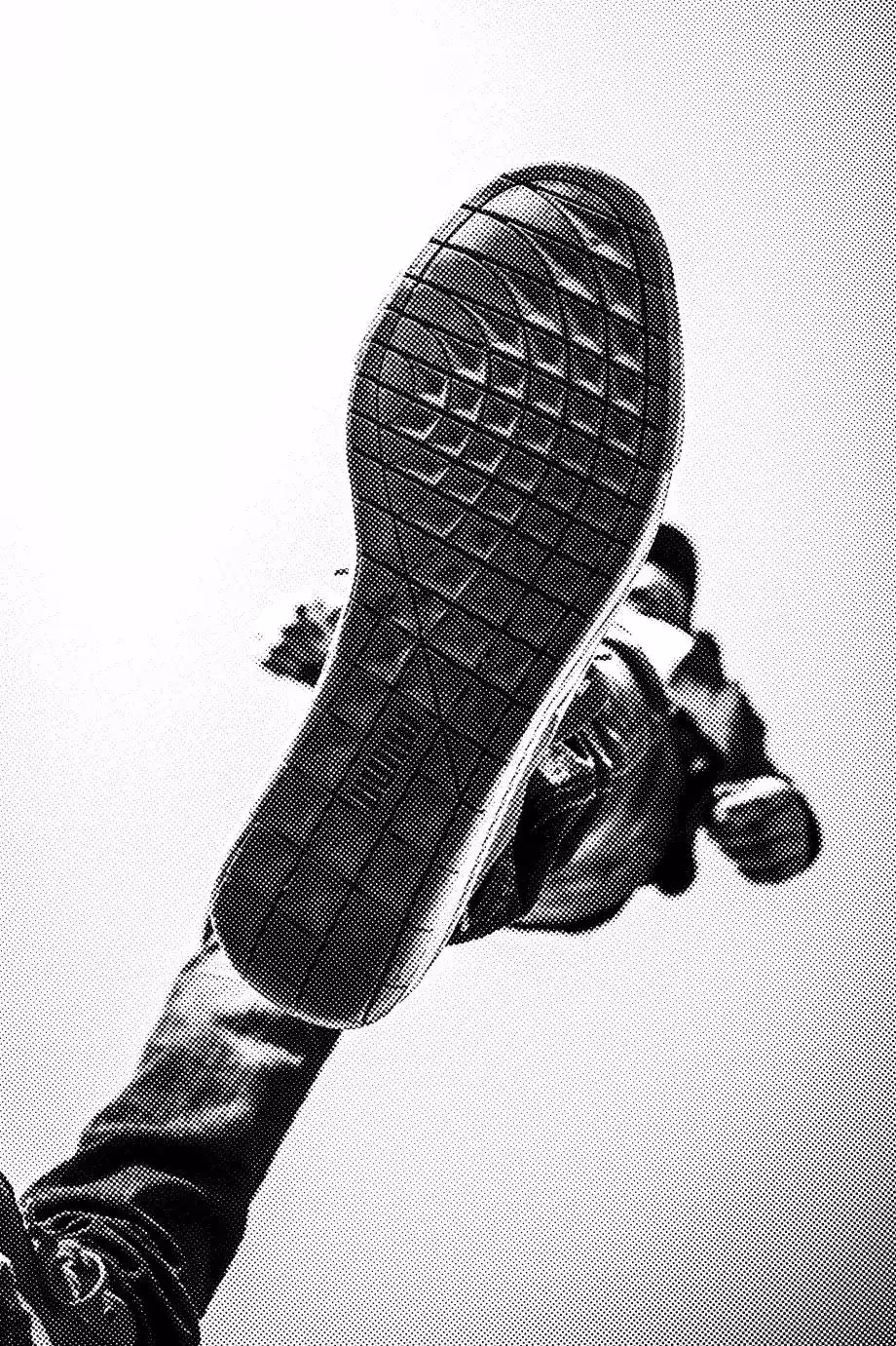 Low-angle view of a person in mid-air with the sole of their shoe facing the camera.