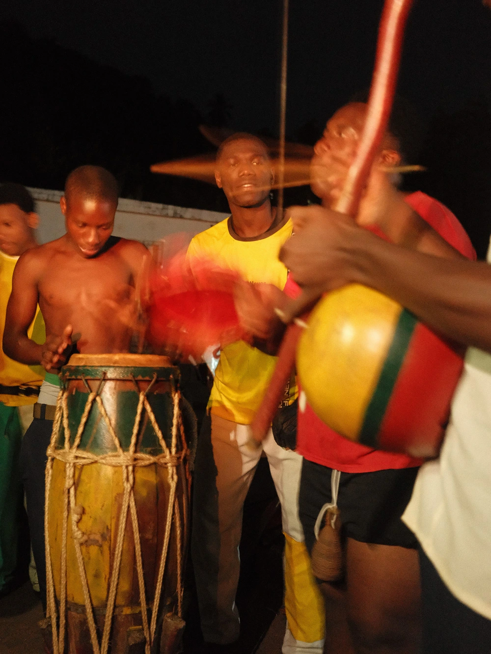Musicians playing drums and berimbau at a night capoeira session