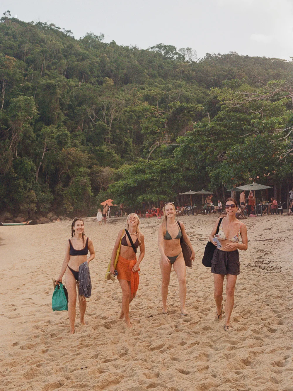 Four women walking along the beach at golden hour