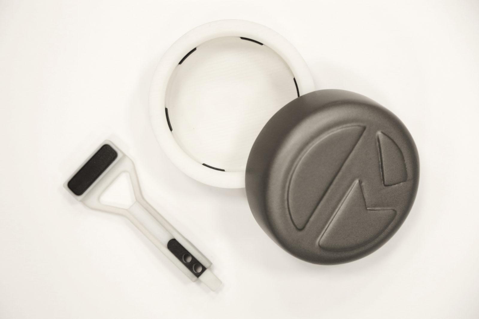 Grasping pincer and packaging lid 3D printed using Stratasys PolyJet 3D printer. The white structural components and black rubber-like grips all in a single print.