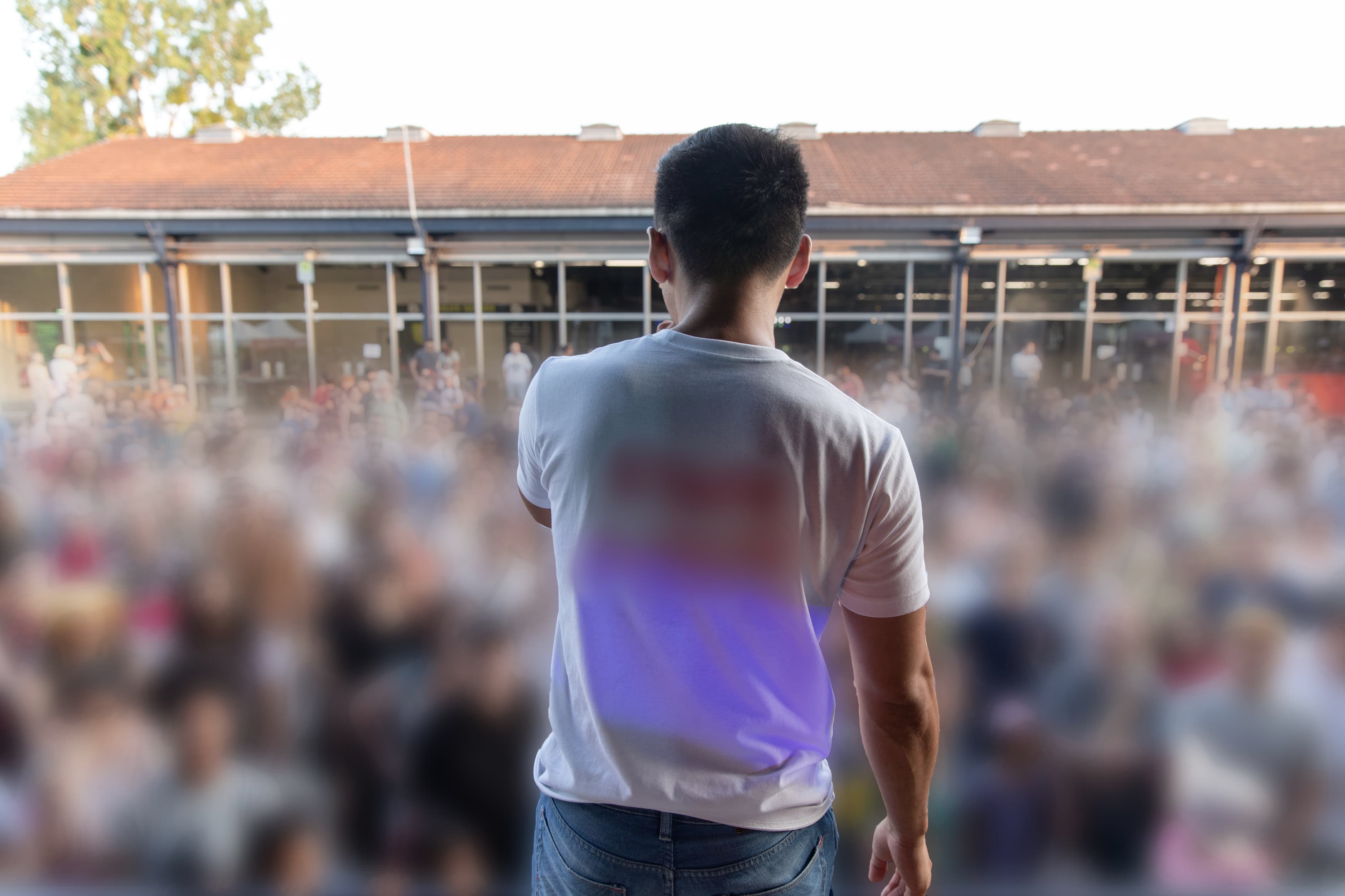 Photographie de Kazu sur scène, devant une grande foule avec son micro, 2023, Paris.