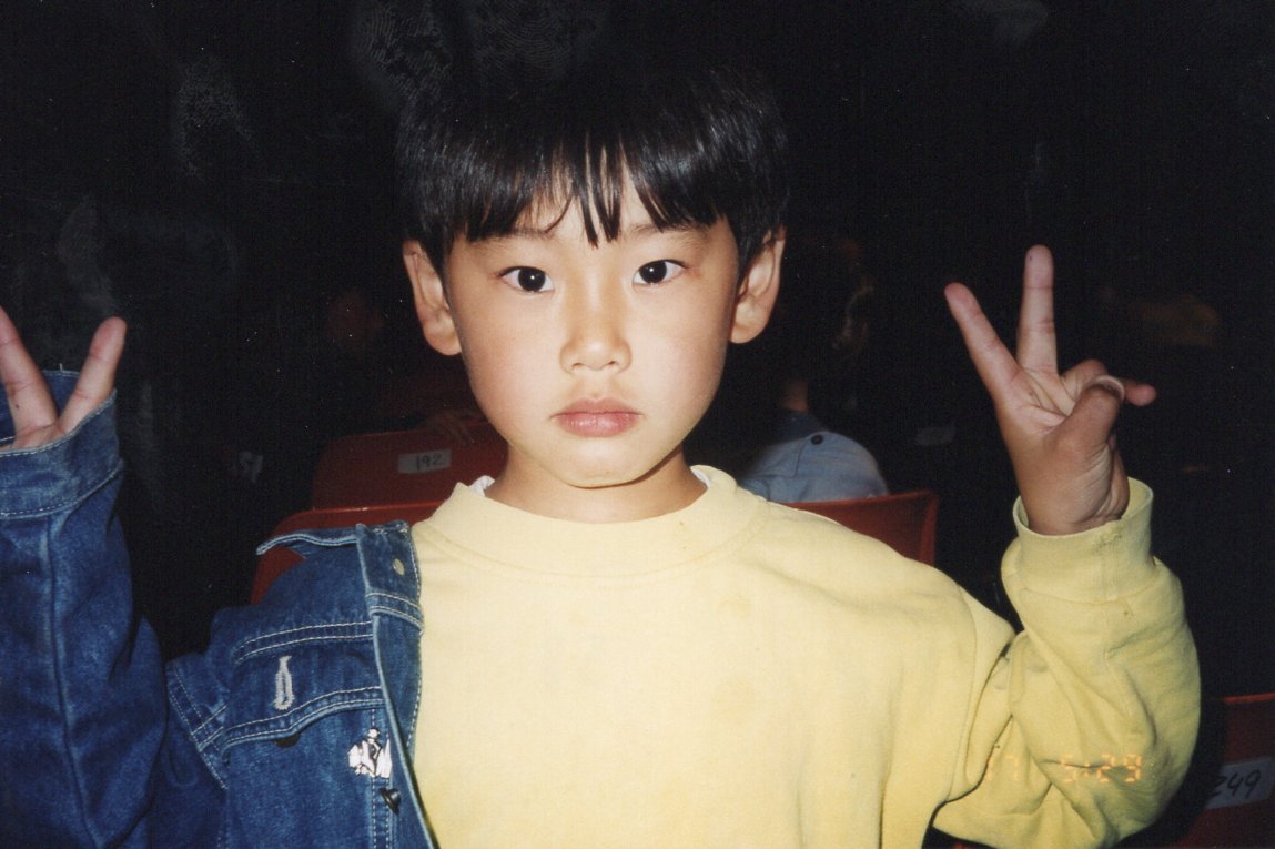 portrait de Kazu enfant 7 ans regardant l’objectif et faisant les signes Peace avec les mains