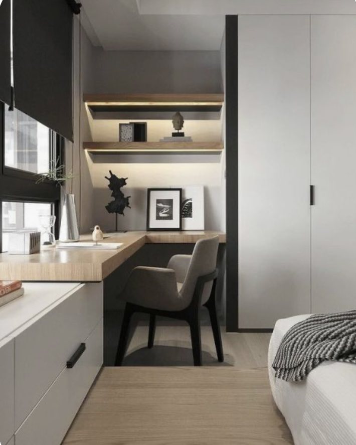 a photo showing a modern corner office in a bedroom. The shelves are pine with back lit led lighting. The counter is made of pine and the office overlooks the window.
