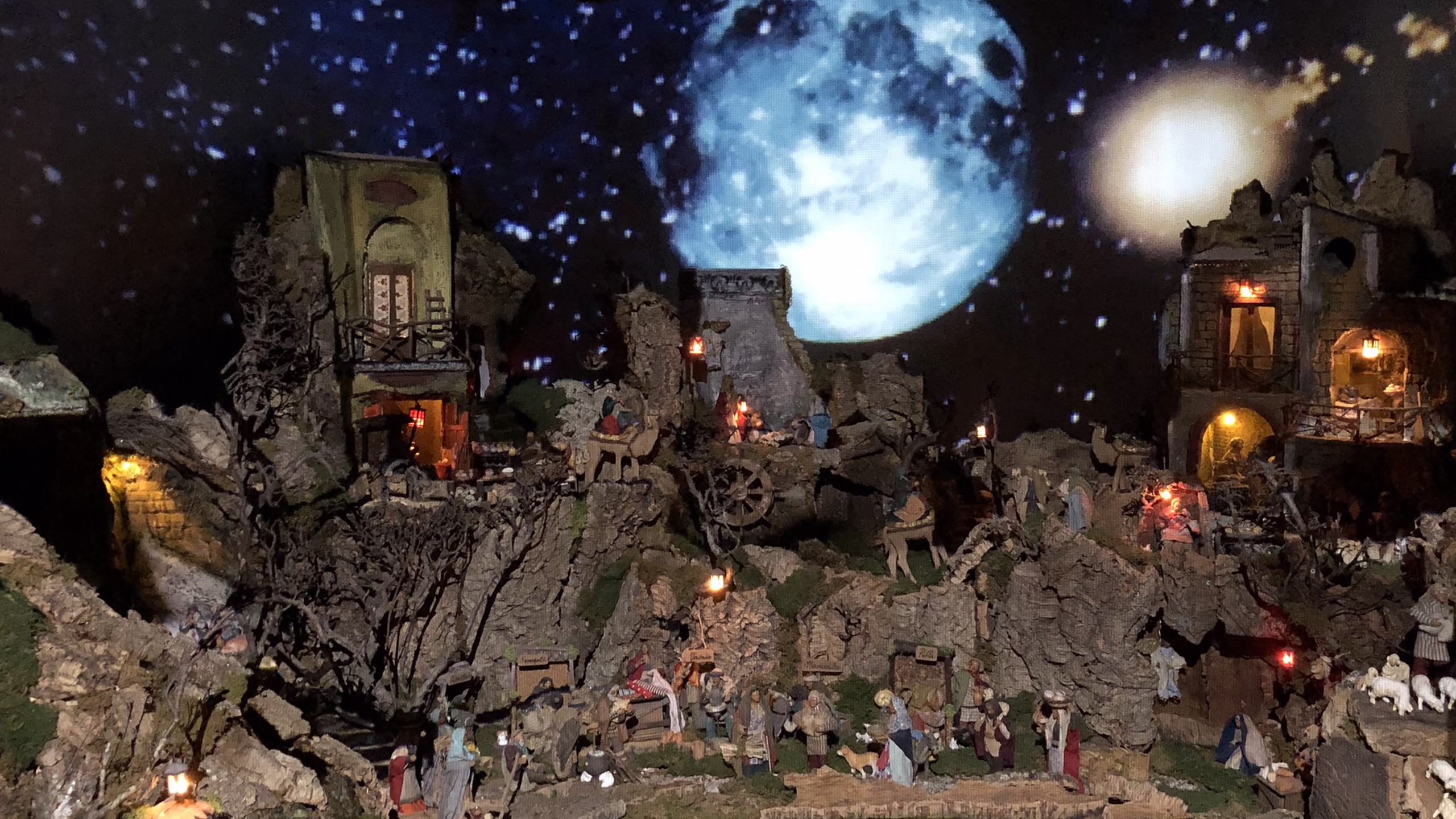 Multimedia scenographic nativity scene with illuminated stone architecture, projections of starry sky and moon, creating a suggestive Christmas atmosphere for professional Christmas set-up.