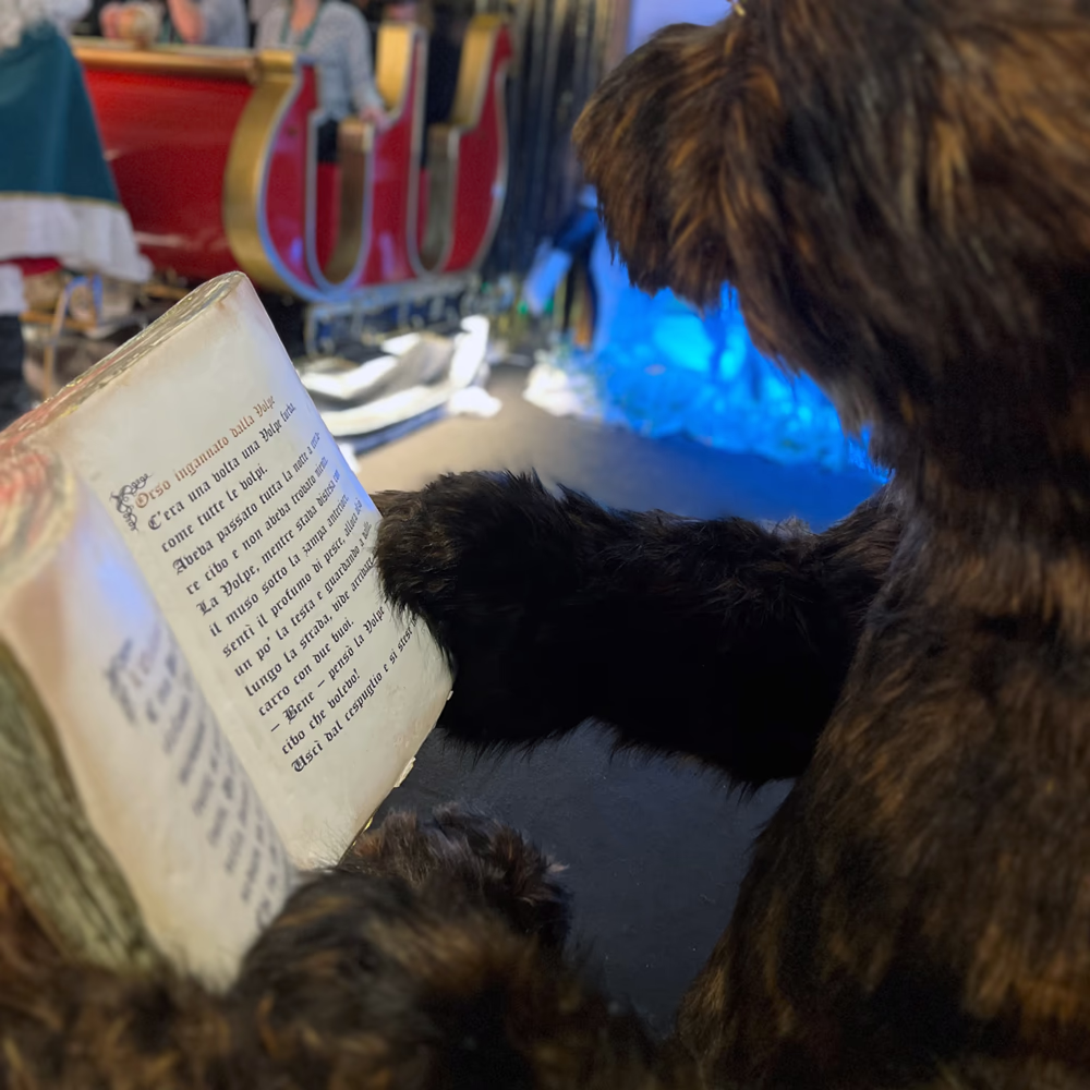 Dettaglio Nonno Orso che legge con illuminazione LED blu interna, mostrando integrazione tecnologie multimediali nell'esperienza narrativa interattiva Menart.