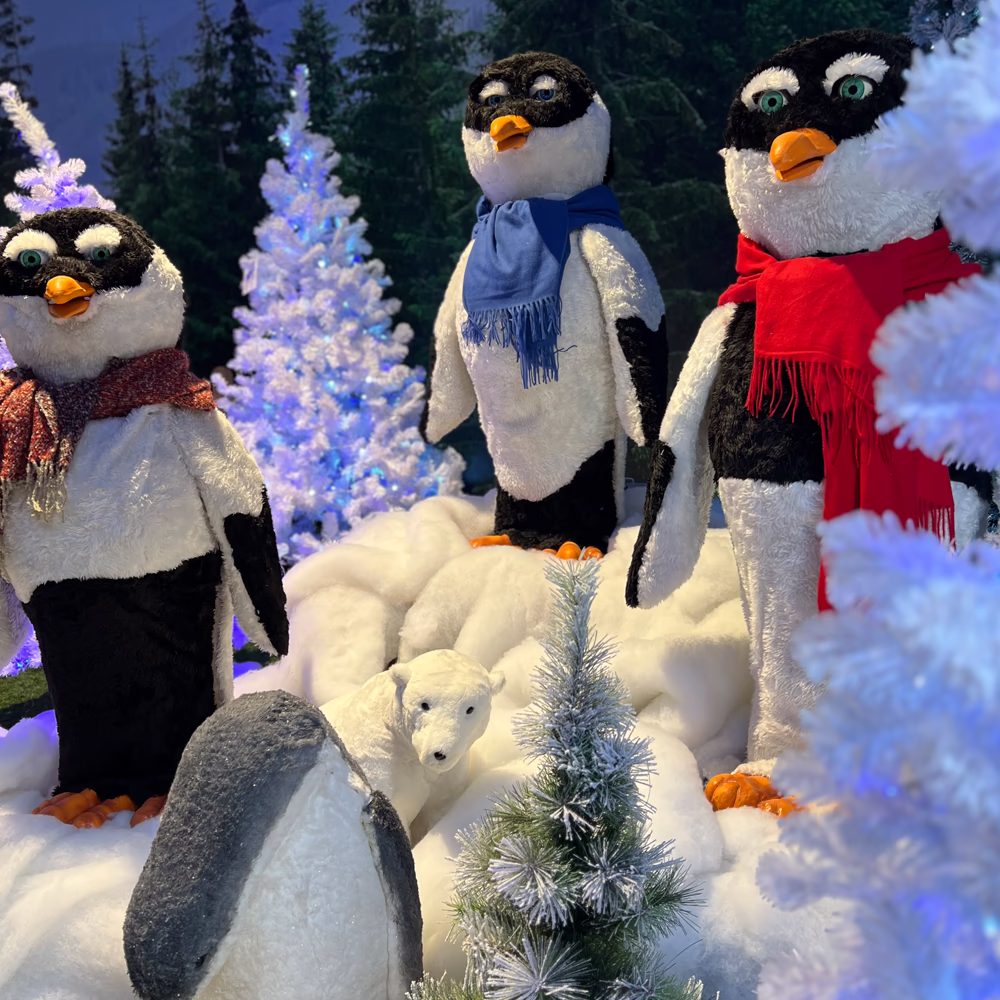 Gruppo Pinguini con orso polare scenografico in ambiente innevato con illuminazione LED blu, creando ecosistema artico completo per eventi natalizi Menart.