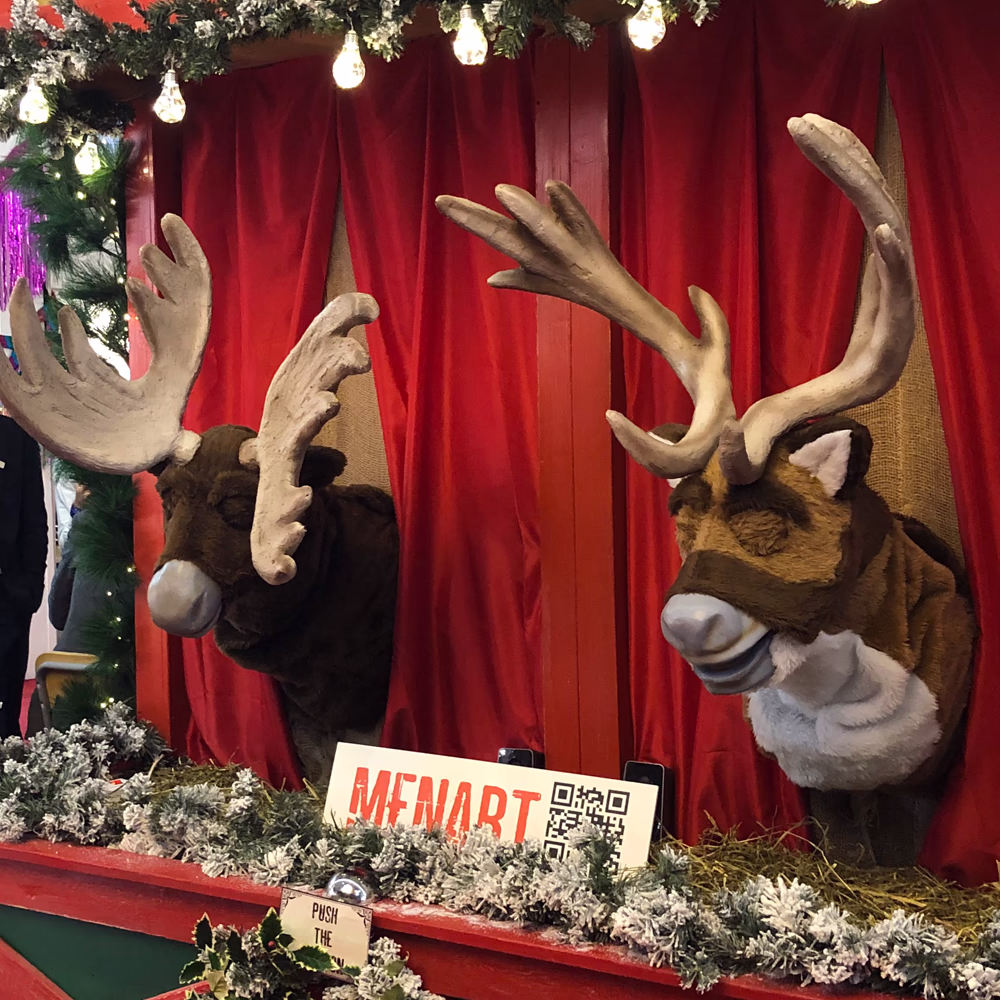Rudolph e Spencer esposti in presentazione Menart con QR code interattivo e sfondo rosso, dimostrando qualità artigianale delle teste scenografiche animate.