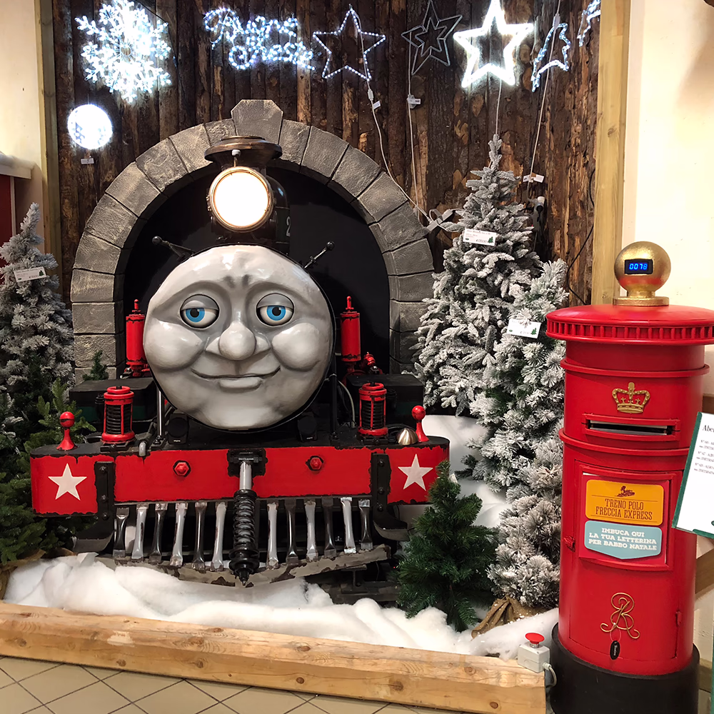 Tommy Express in allestimento natalizio completo con tunnel scenografico, decorazioni LED stellari e cassetta postale interattiva, creando villaggio ferroviario incantato Menart.