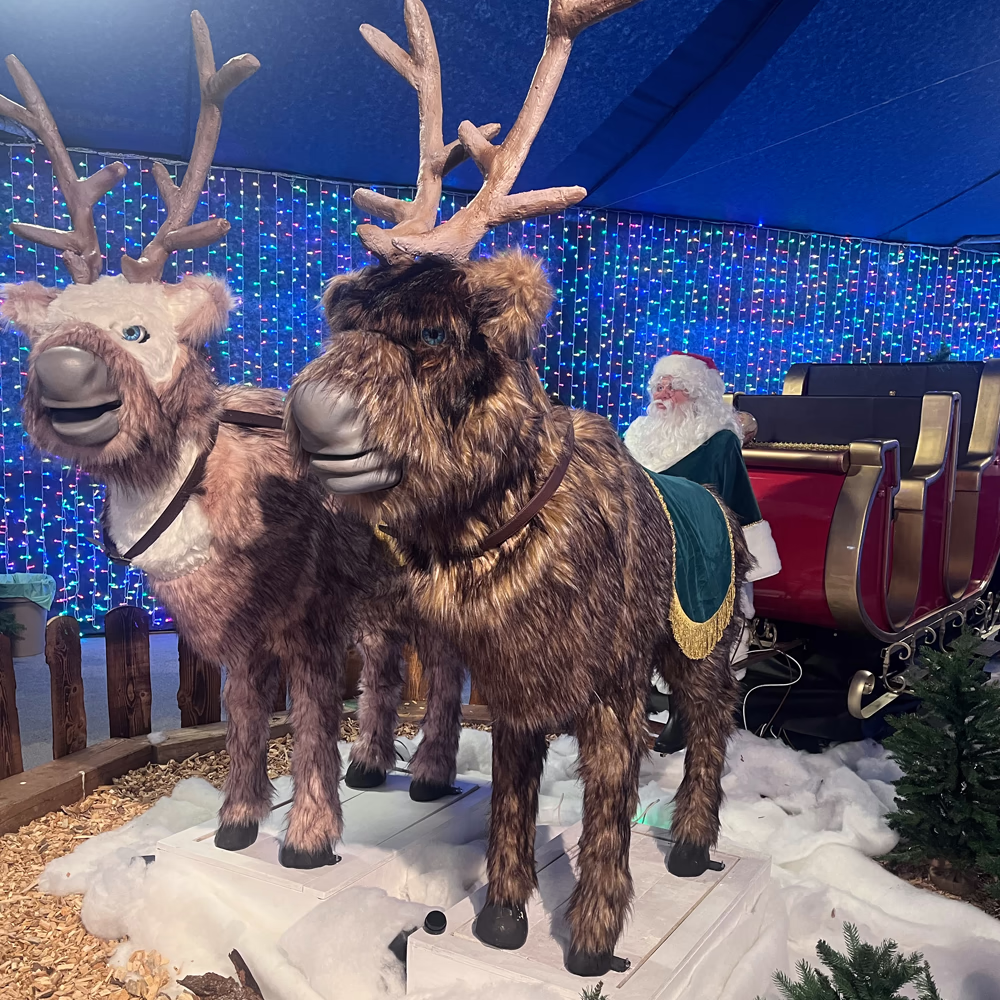 Gruppo renne multicolori Slitta Express VR con Santa Claus e illuminazione LED blu, installazione scenografica completa per esperienze VR natalizie coinvolgenti.