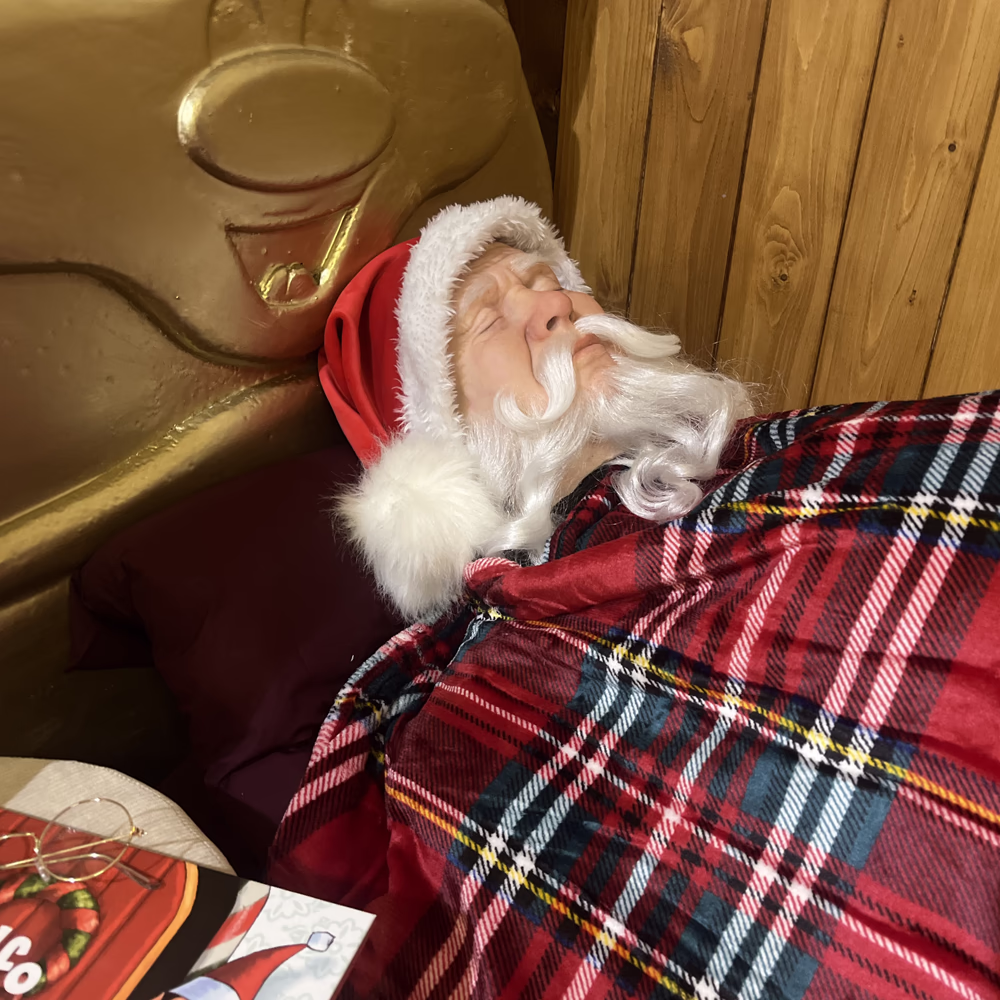 Installazione scenografica immersiva con Babbo Natale animato, tessuti tradizionali e arredamento realistico per esperienza natalizia completa in "La Casa Magica".