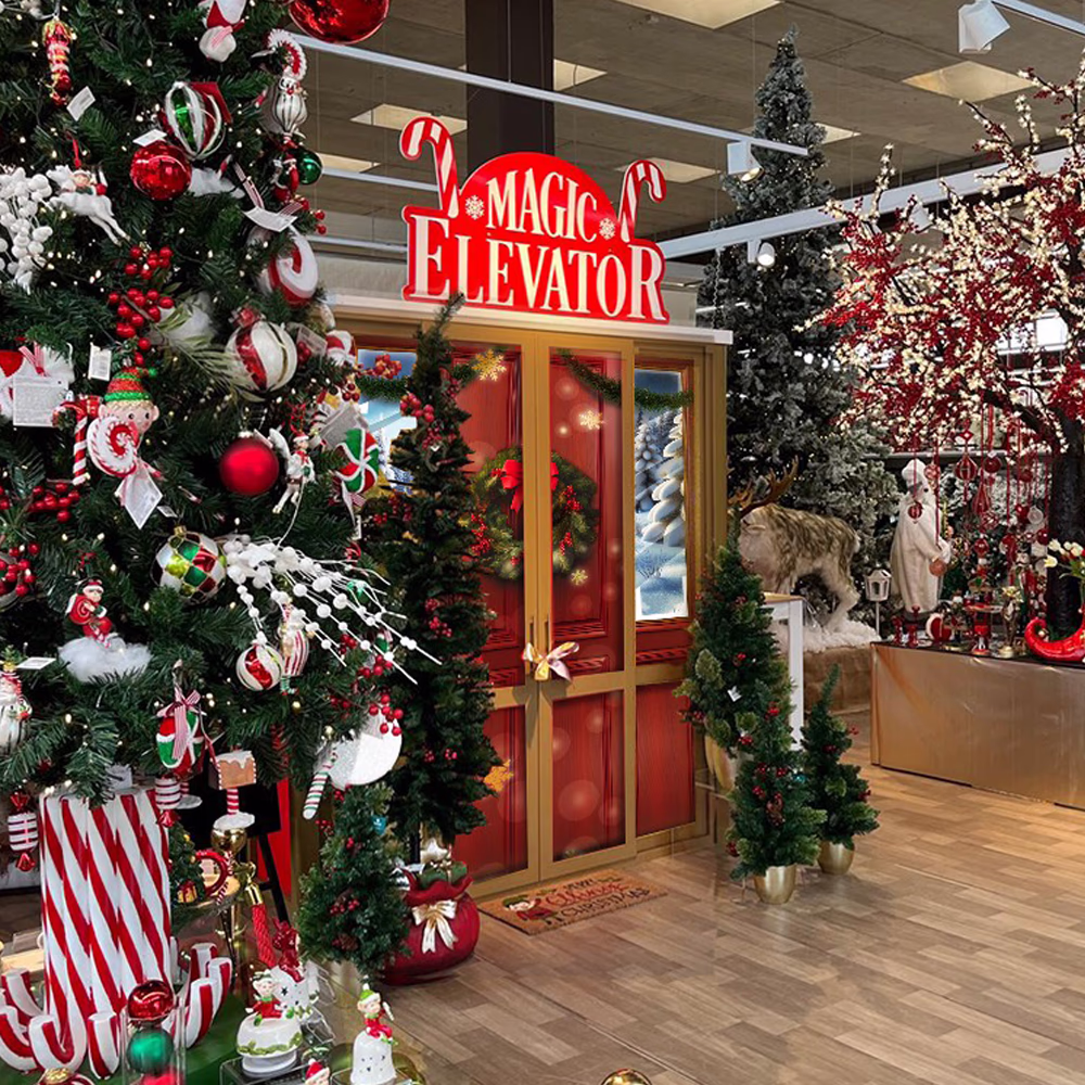 Installazione "Magic Elevator" in centro commerciale con decorazioni natalizie circostanti, integrando tecnologia multimediale e scenografia tradizionale per atmosfera festiva immersiva.