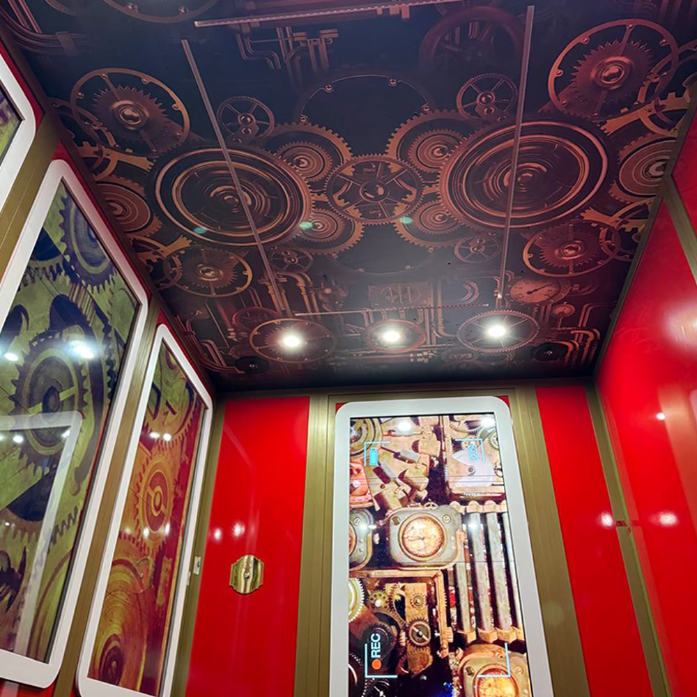 Interno "Magic Elevator" con soffitto meccanico animato, illuminazione integrata, schermi digitali interattivi e finiture dorate per esperienza scenografica coinvolgente e tecnologicamente avanzata.