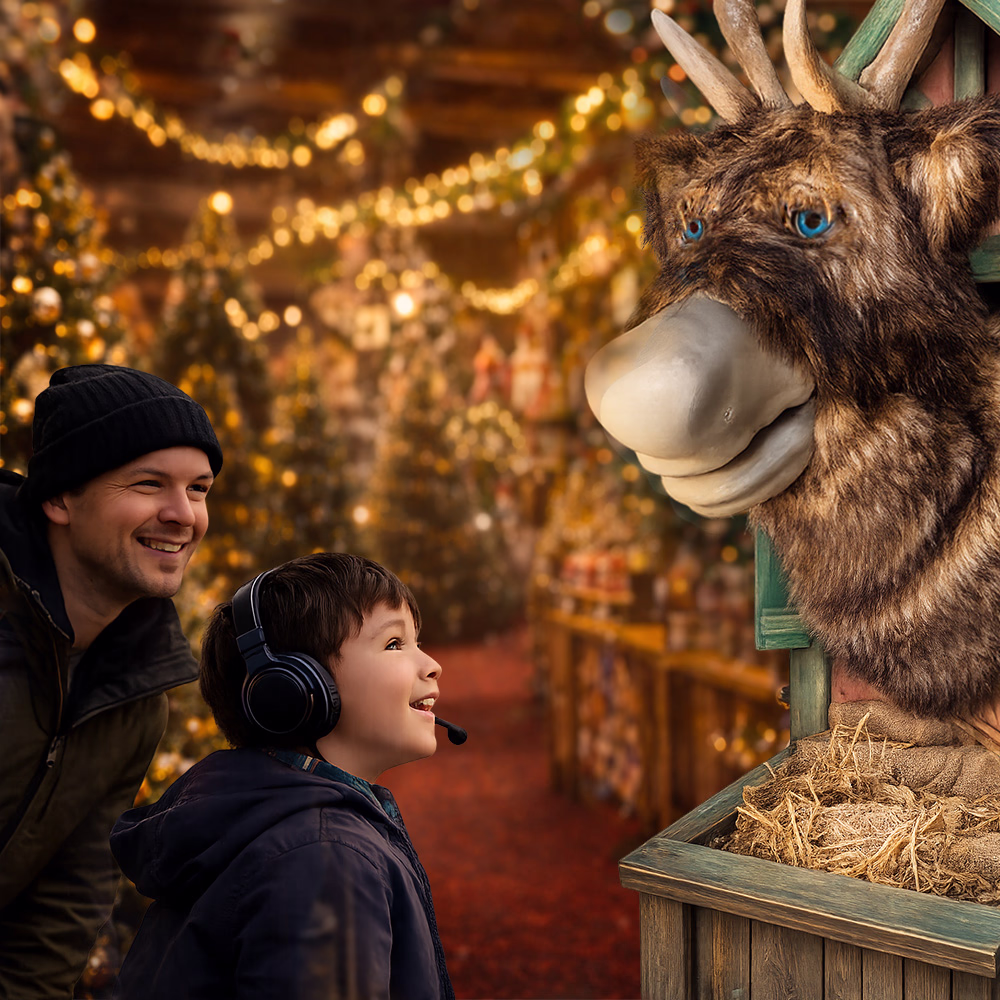 A child with headphones and a smiling man look at an animated Christmas figure that looks like a reindeer at an illuminated holiday market.