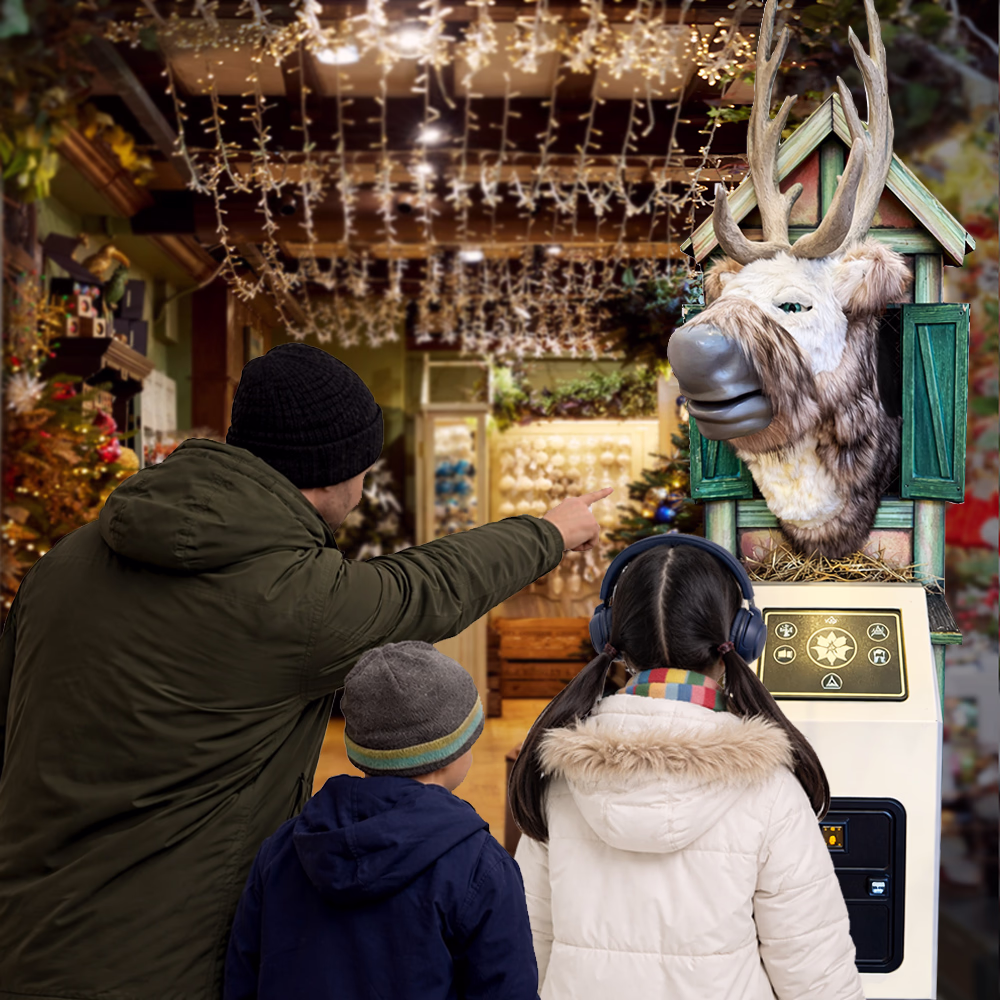 Man and two children in winter coats interact with an animatronic reindeer machine in an environment decorated for Christmas.
