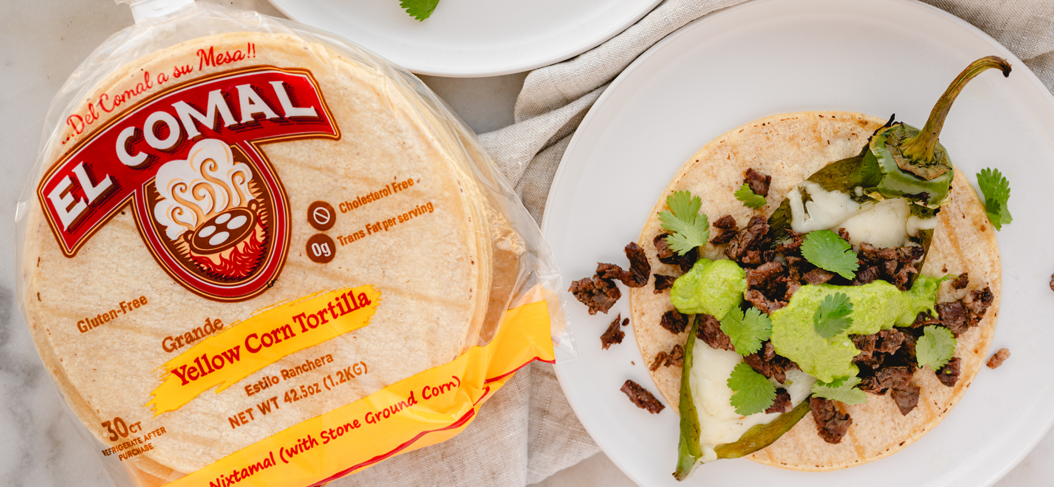 Corn tortilla package and taco with seasoned meat, cilantro, and roasted pepper