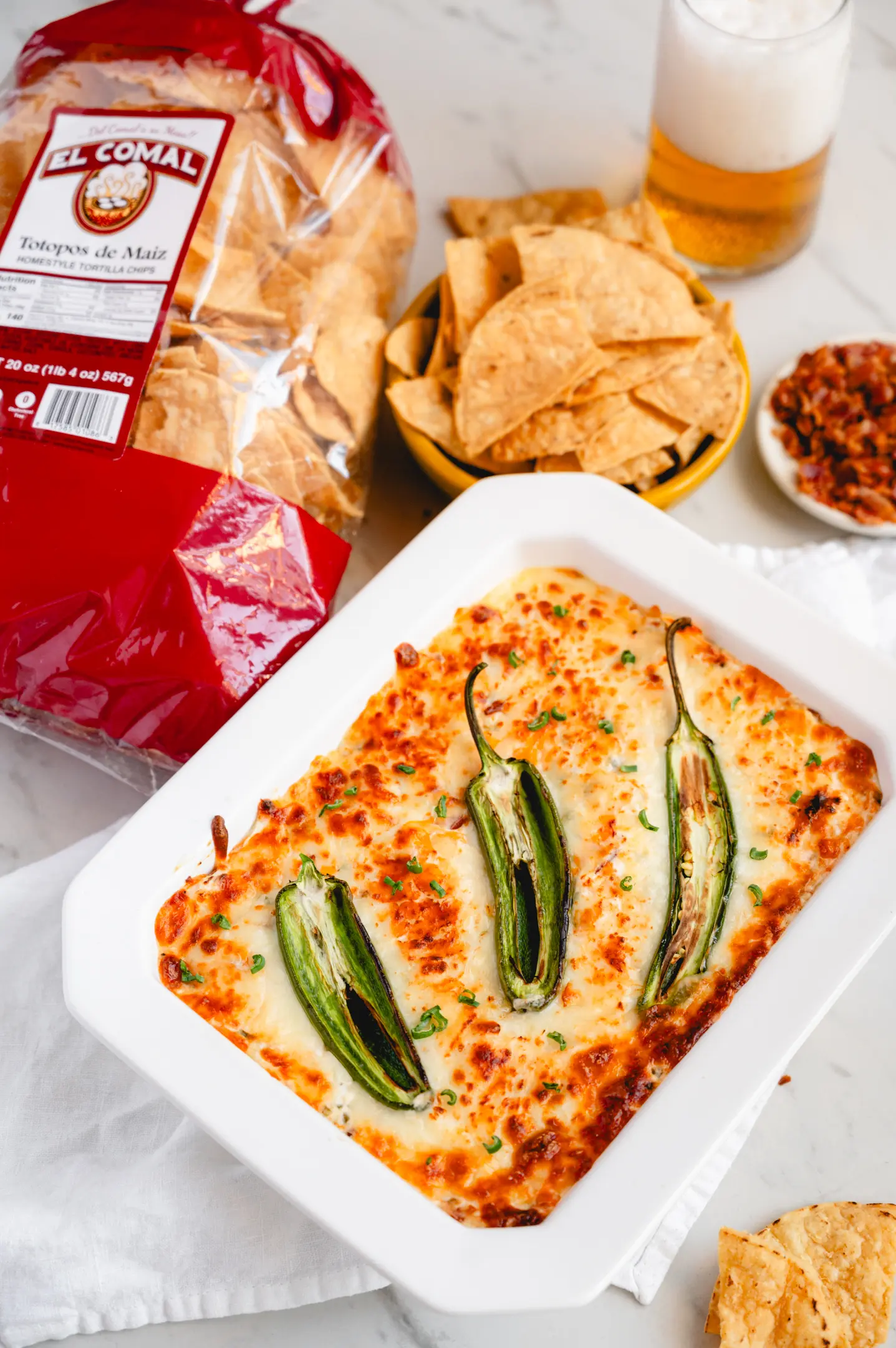 Tortilla chips, bowl of chips, and baked casserole with cheese and green peppers