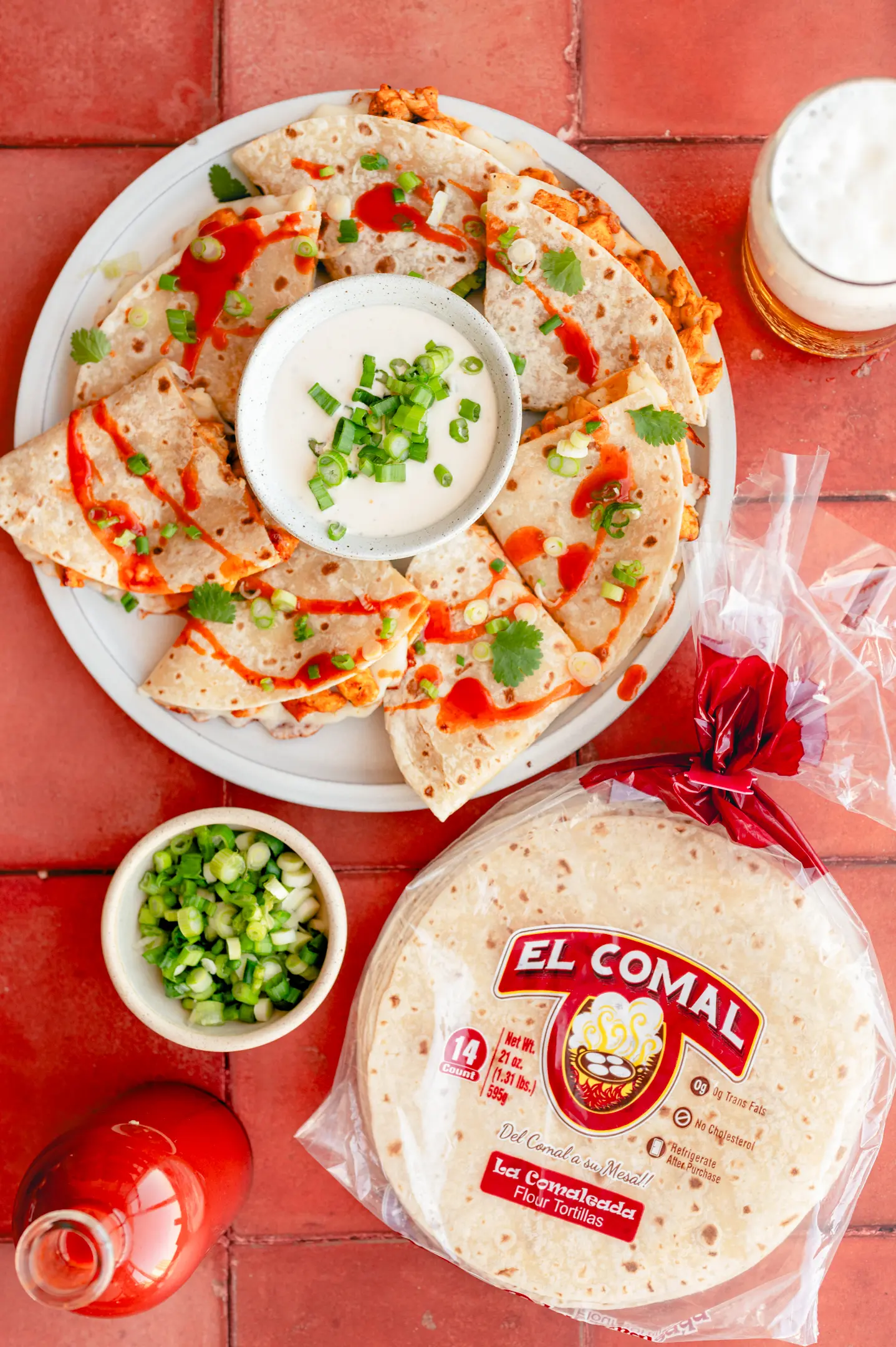 Quesadilla slices with sour cream dip, tortilla package, and chopped green onions