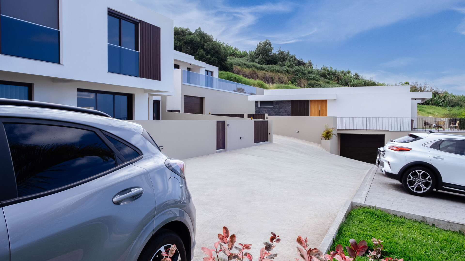 Vista exterior de residências contemporâneas com entrada de automóveis e carros estacionados