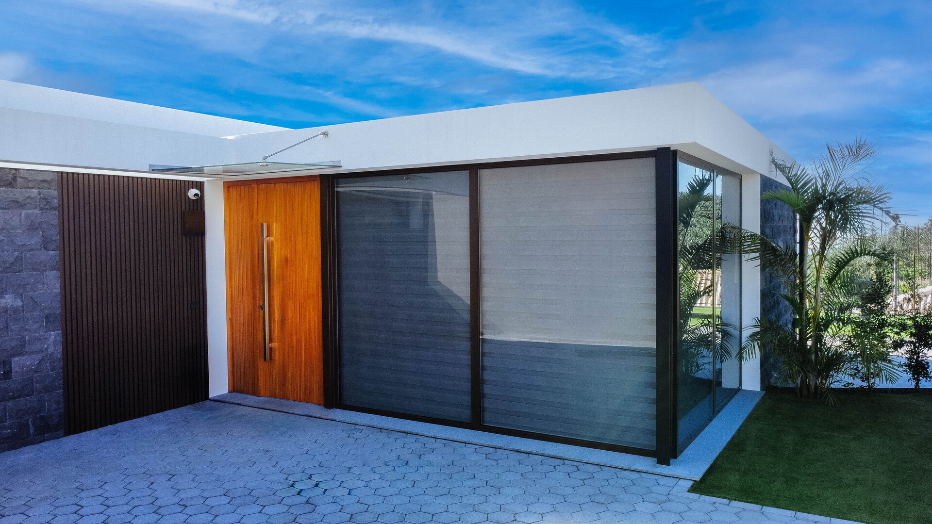 Entrada de moradia moderna com porta em madeira e ampla janela envidraçada.