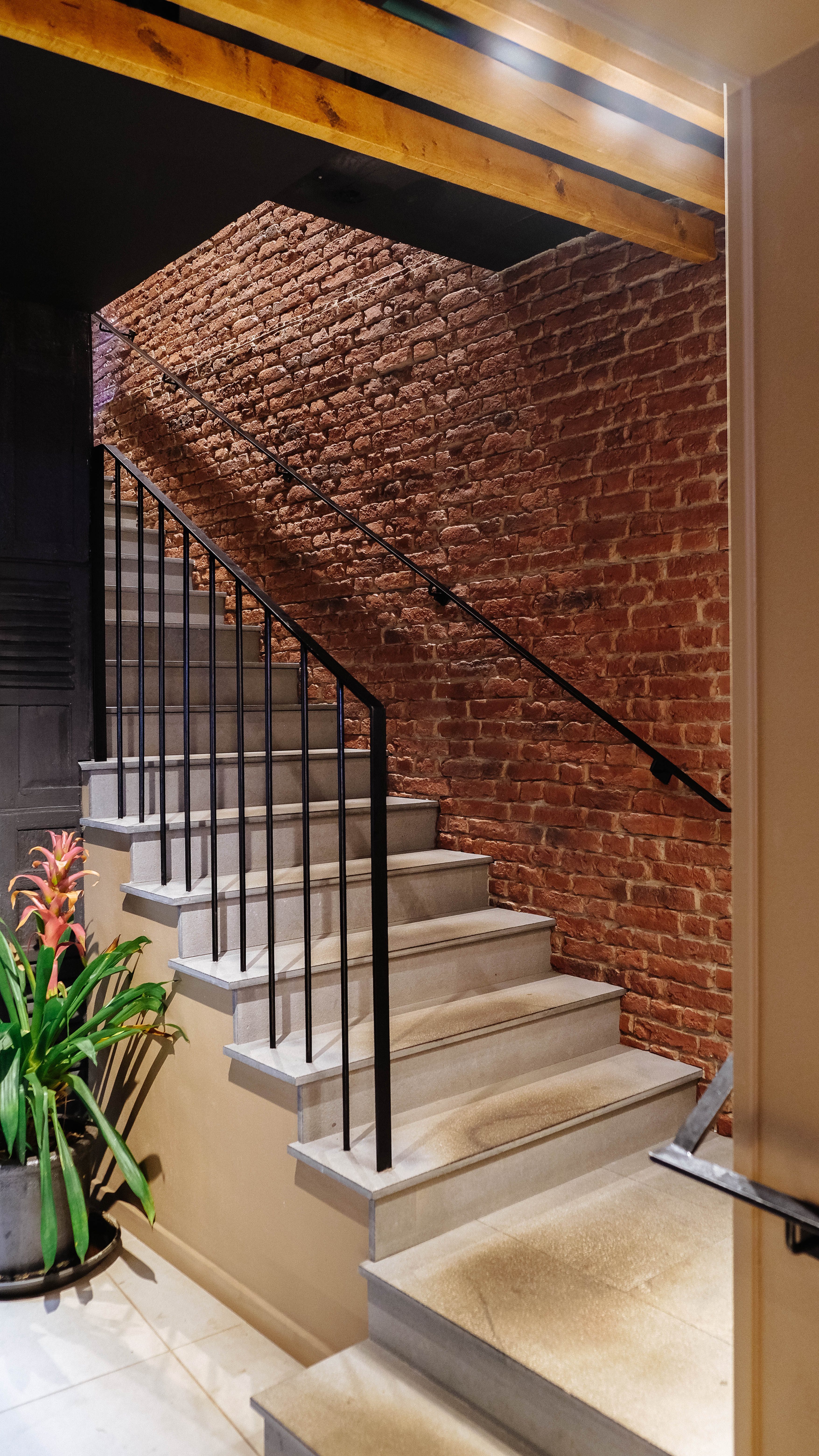 Escadas com corrimão de ferro e parede de tijolo