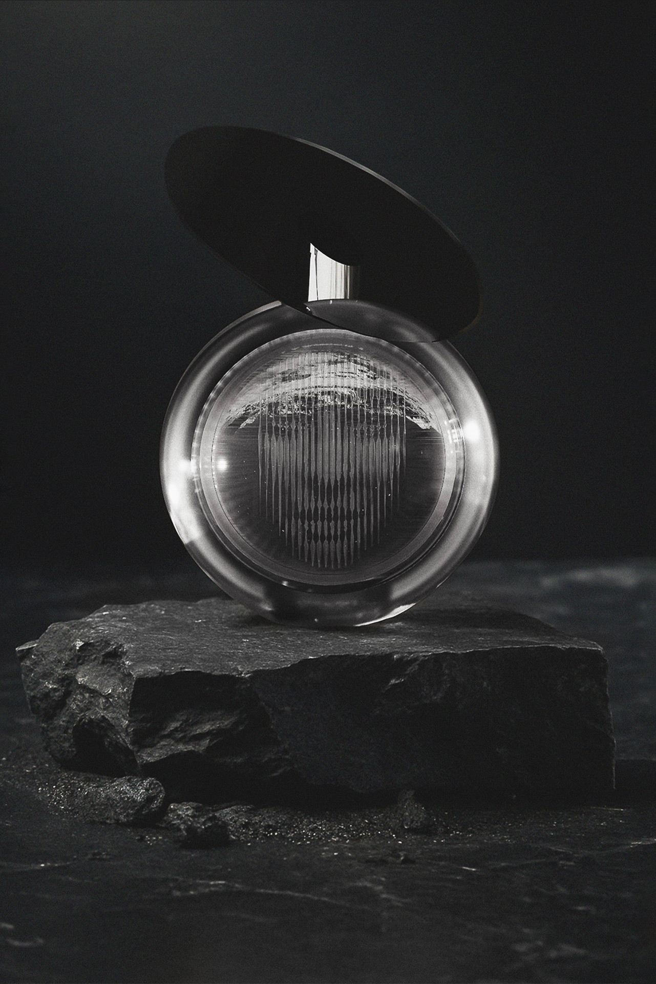 Dark product visualization of a circular glass perfume bottle on stone — artistic still life by TOMA Studio.