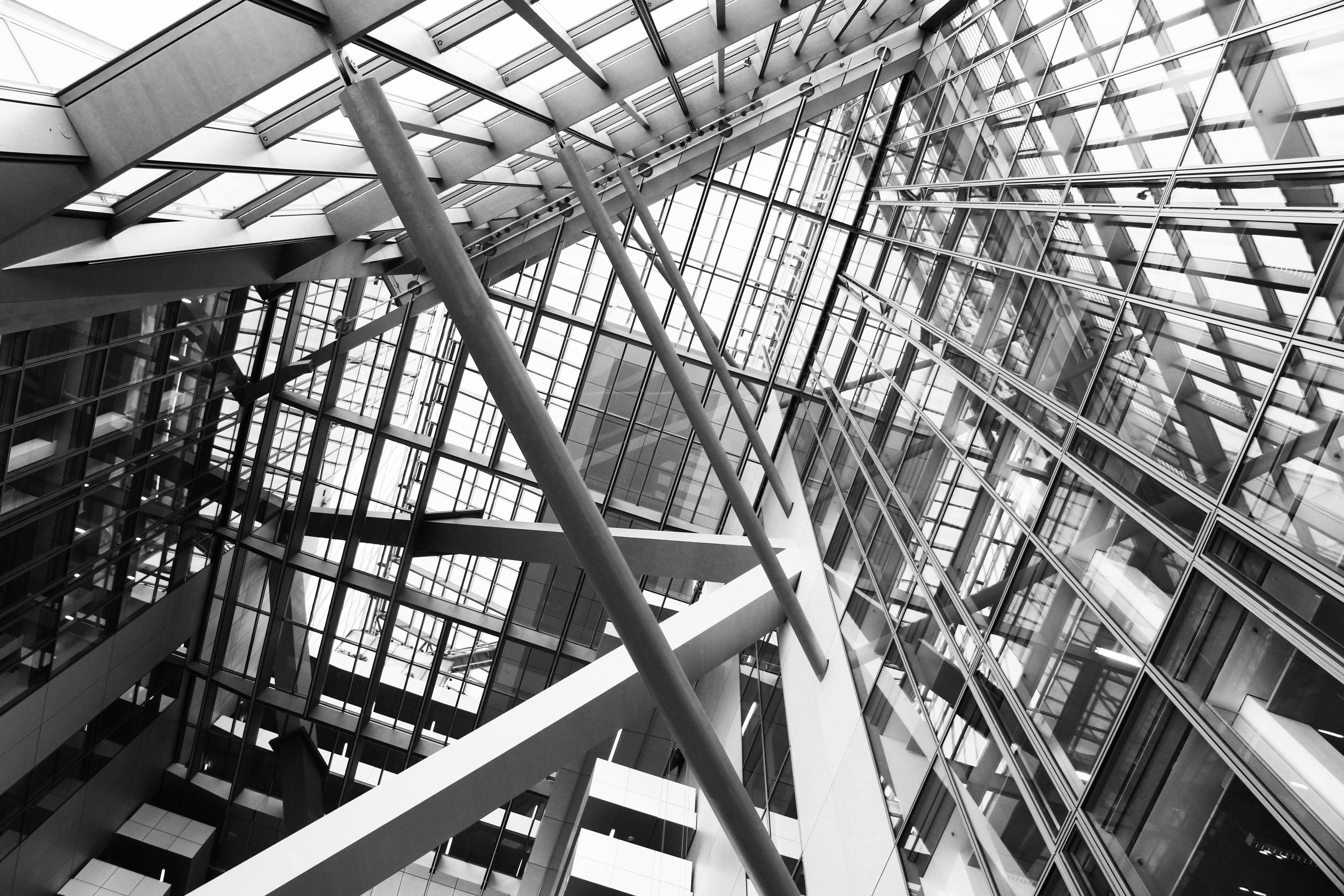 Upward view of steel and glass structure showing intersecting beams — architectural photography by TOMA Studio.