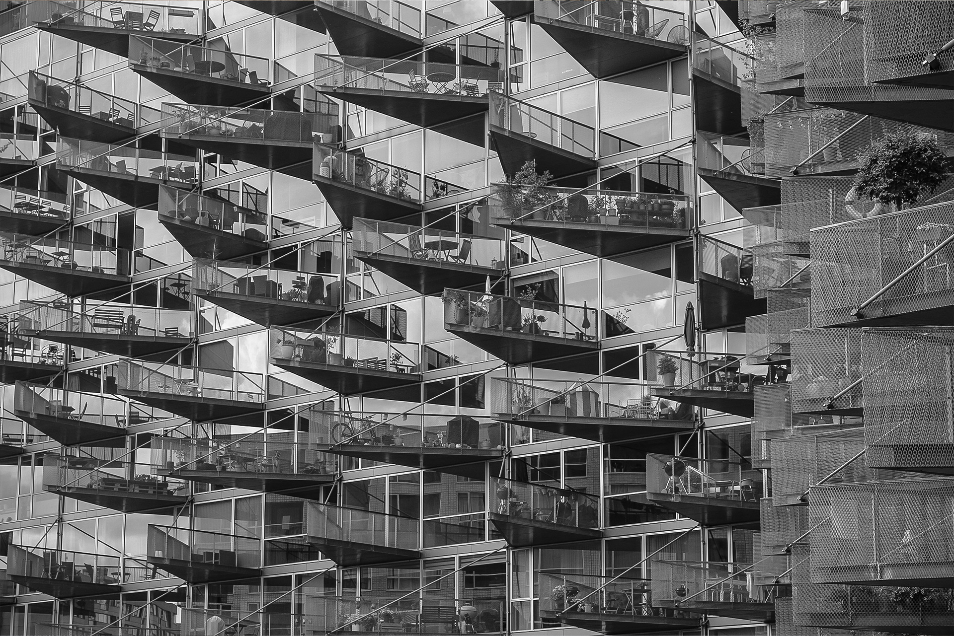 Black-and-white photograph of a modern residential façade with angular balconies — architectural photography by TOMA Studio.