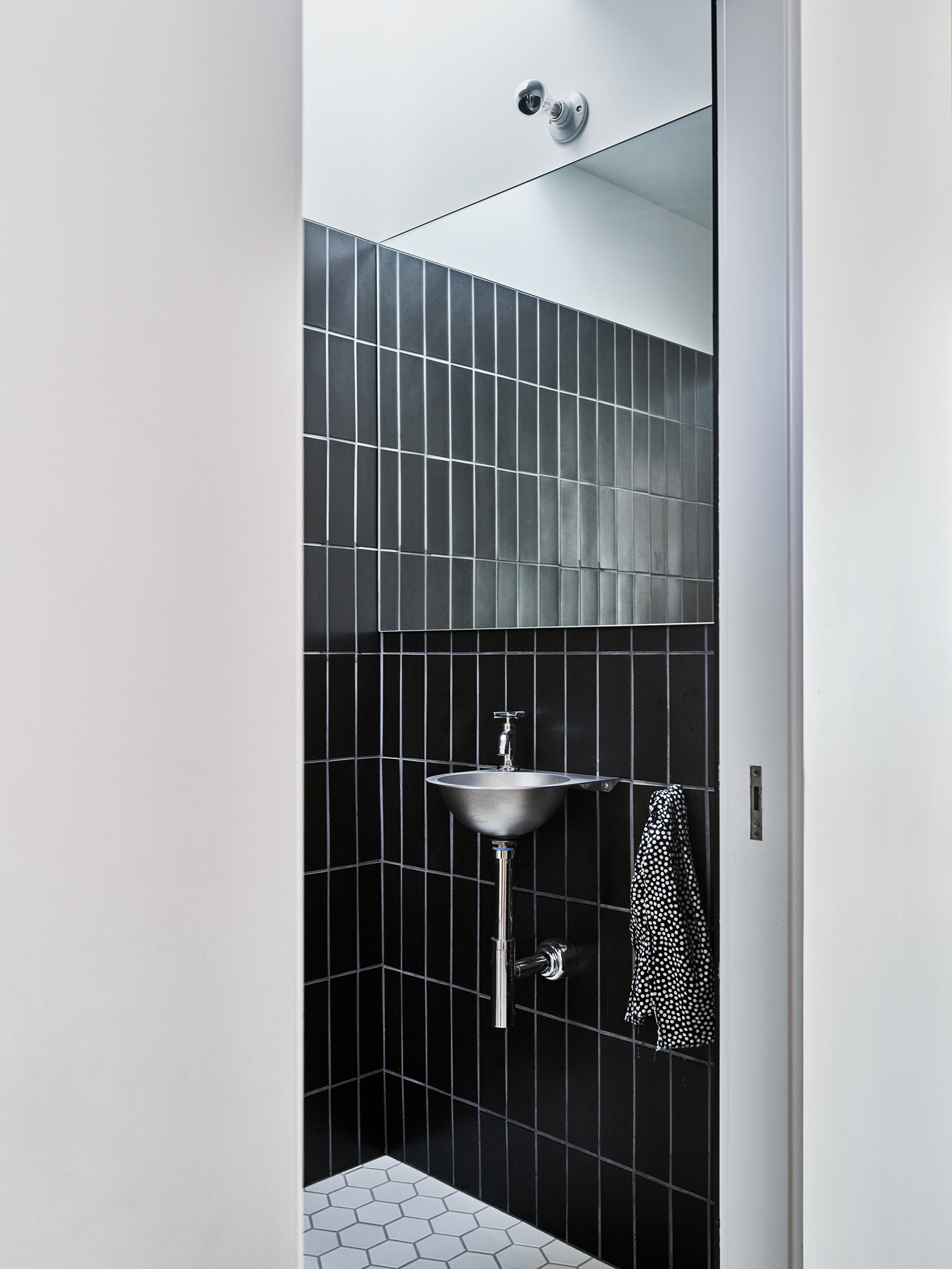 bathroom with black tile and stainless fixtures