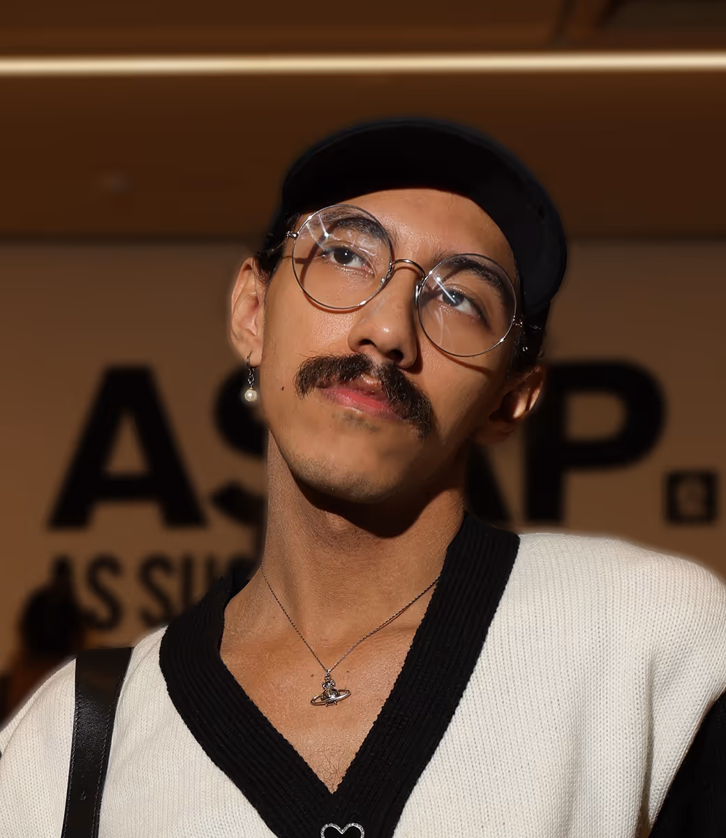 Homem da pele parda, com óculos redondos, bigode e boné na cabeça