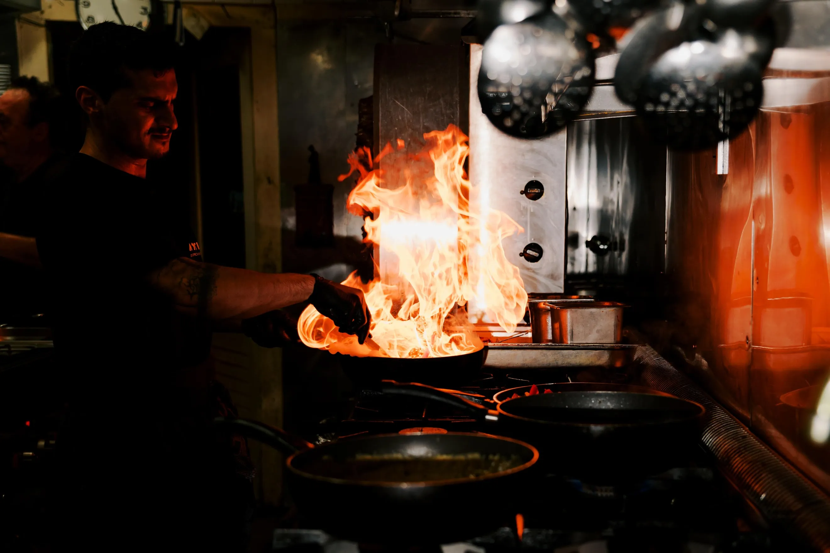 Chef-kok flambeert gerecht in open keuken van Grieks restaurant Mythos in Hoeven