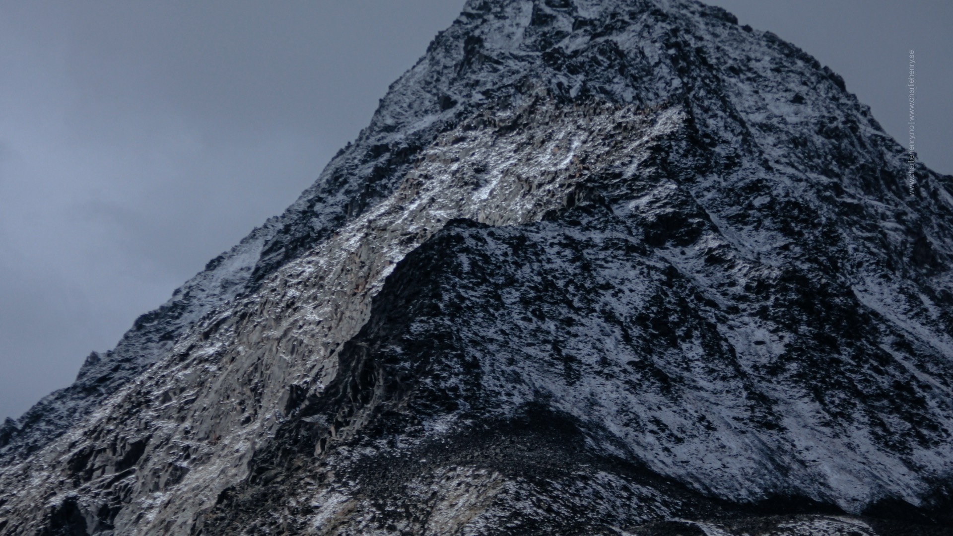 Sharp peak of a snow-covered mountain in the Altai range, highlighted by low winter light — dramatic landscape photography by Charlie Henry.