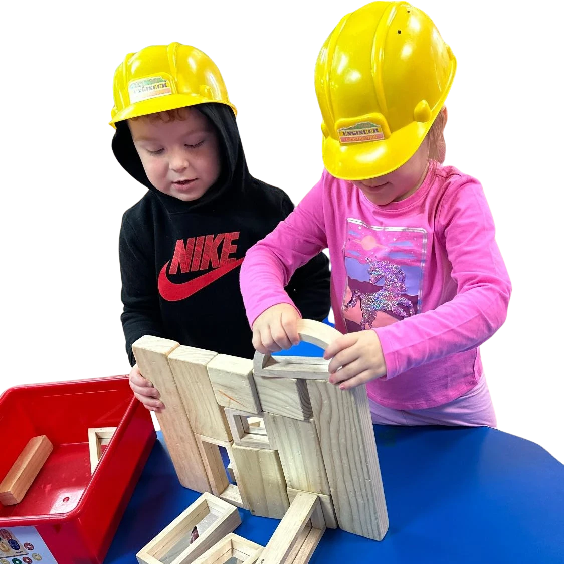 Young girls wearing construction helmets playing with building blocks