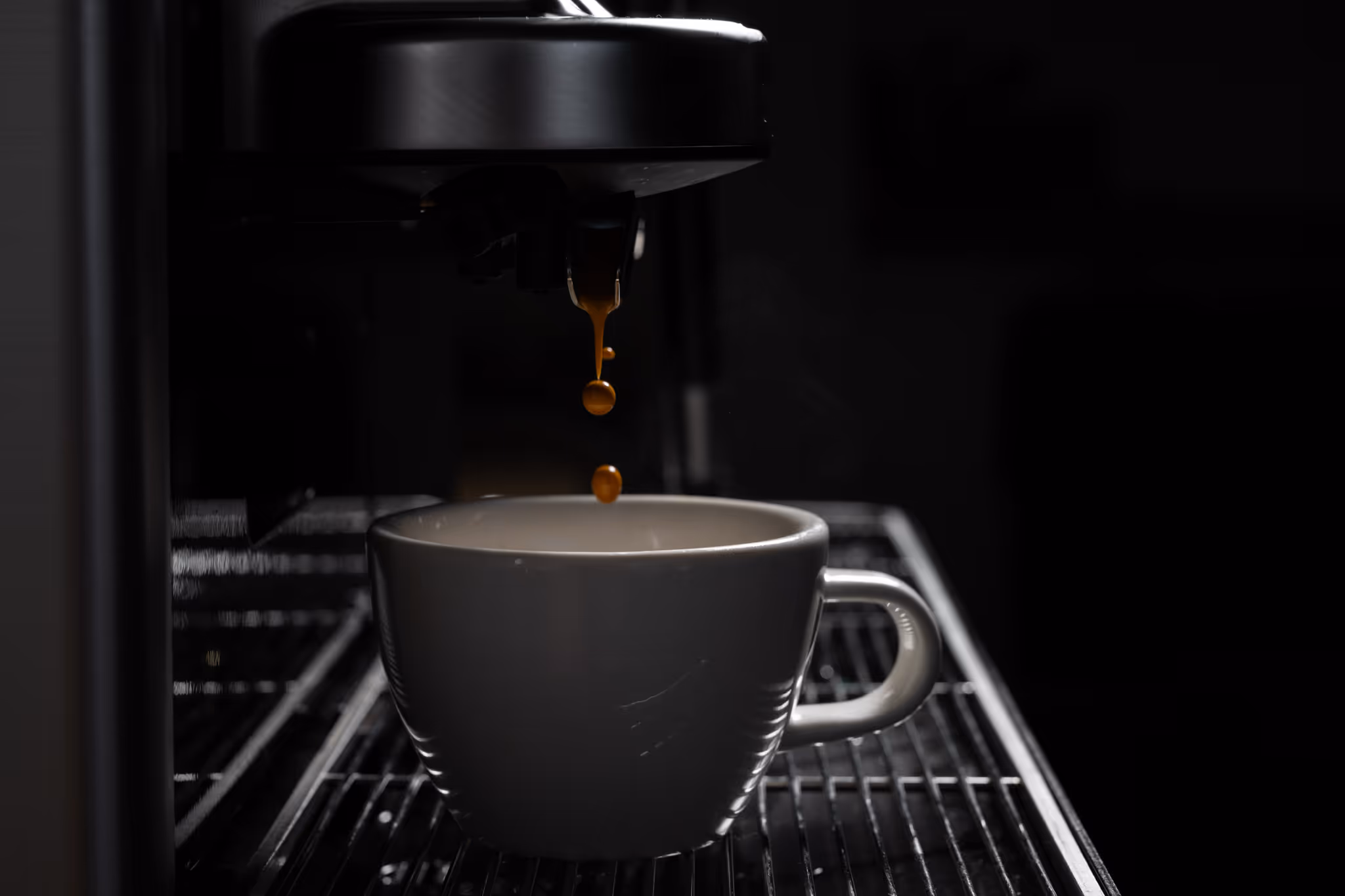 Close-up of coffee machine brewing espresso into two black and white cups.