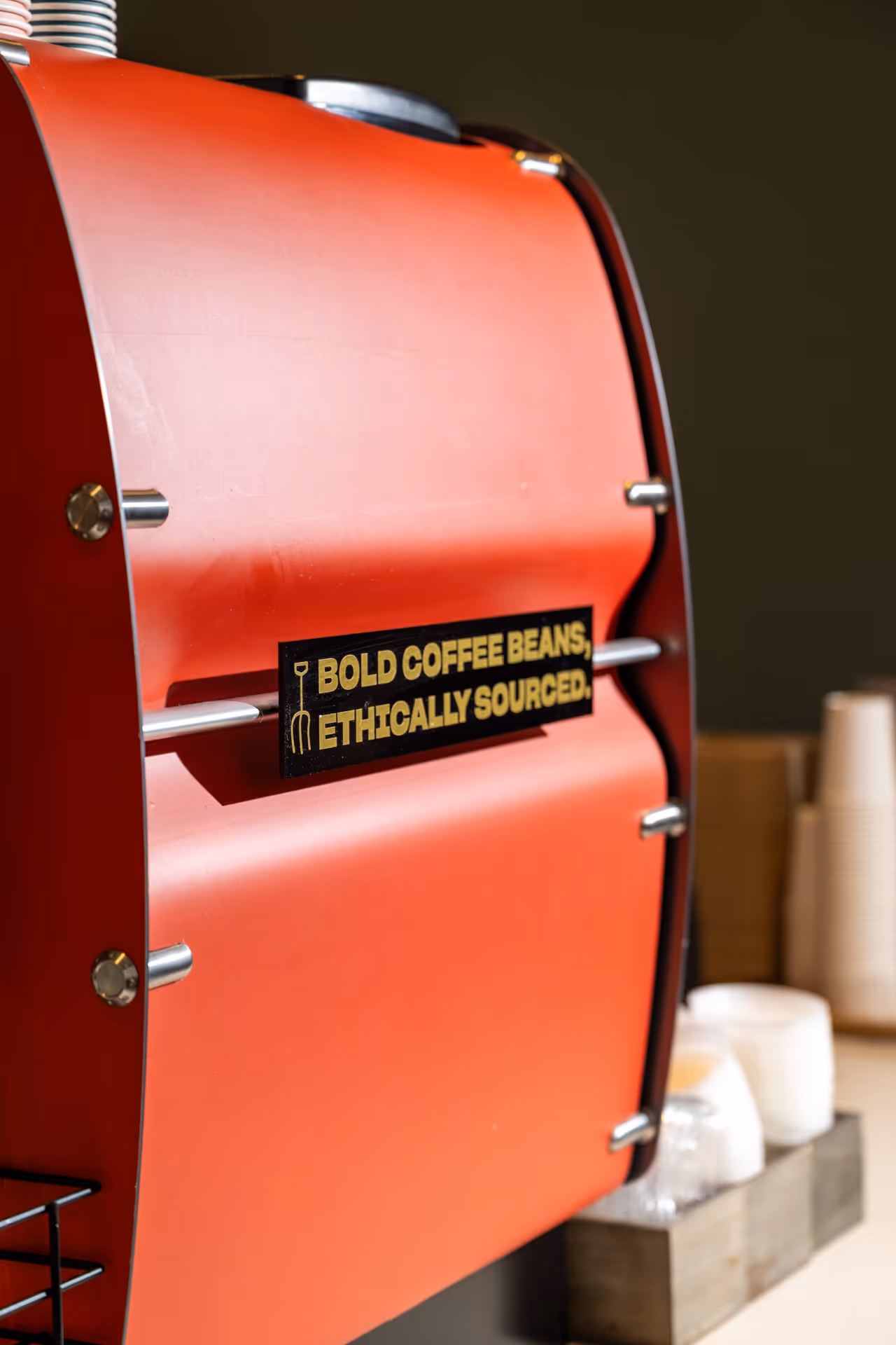 Close-up of a red coffee roaster with a sign that says 'Bold coffee beans, ethically sourced.'