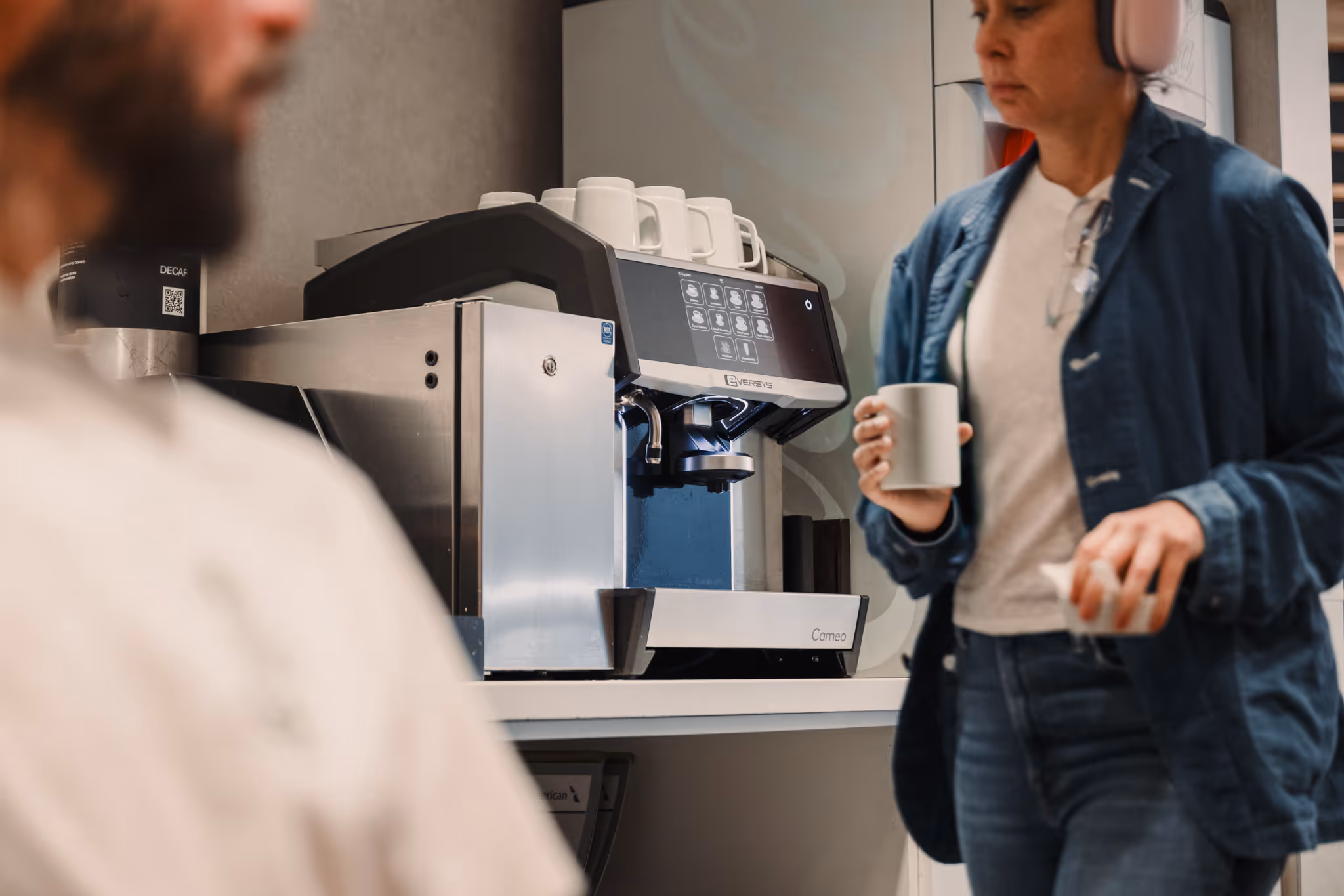 Close-up of an EVERSYS Cameo espresso machine dispensing coffee into a pink cup.
