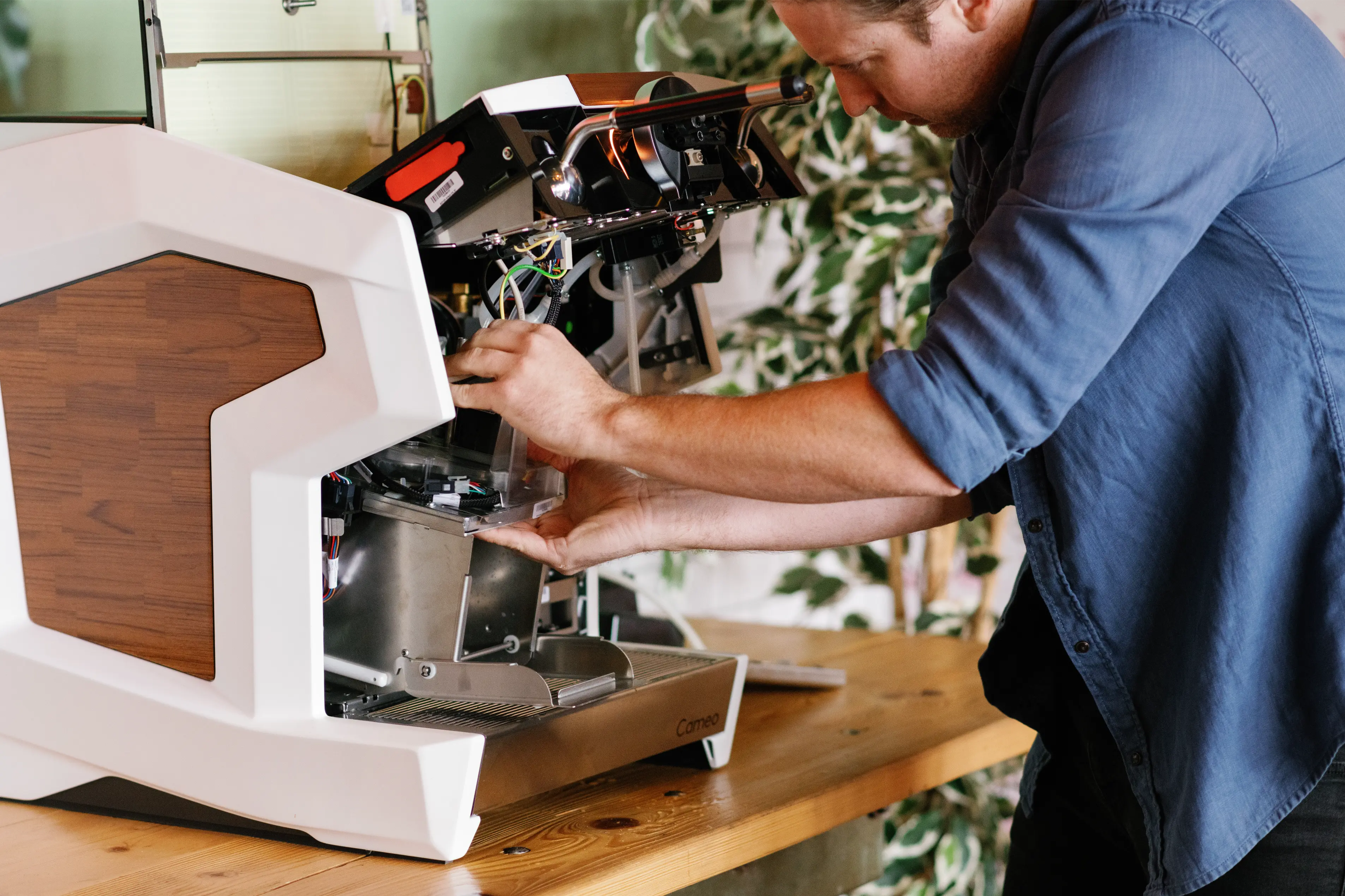 Modern coffee machine with digital display brewing coffee into a white cup on a wooden table.