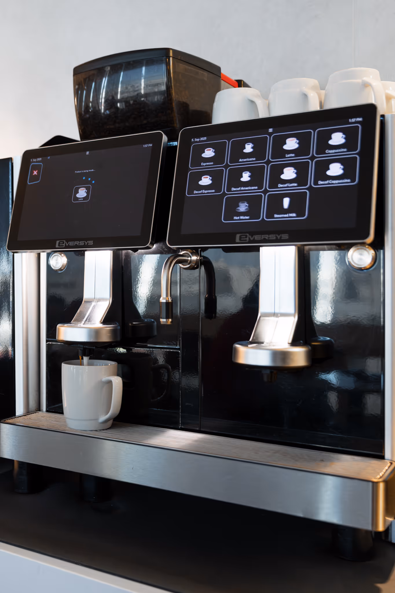 Modern automatic coffee machine dispensing coffee into a white mug with a selection screen showing drink options.
