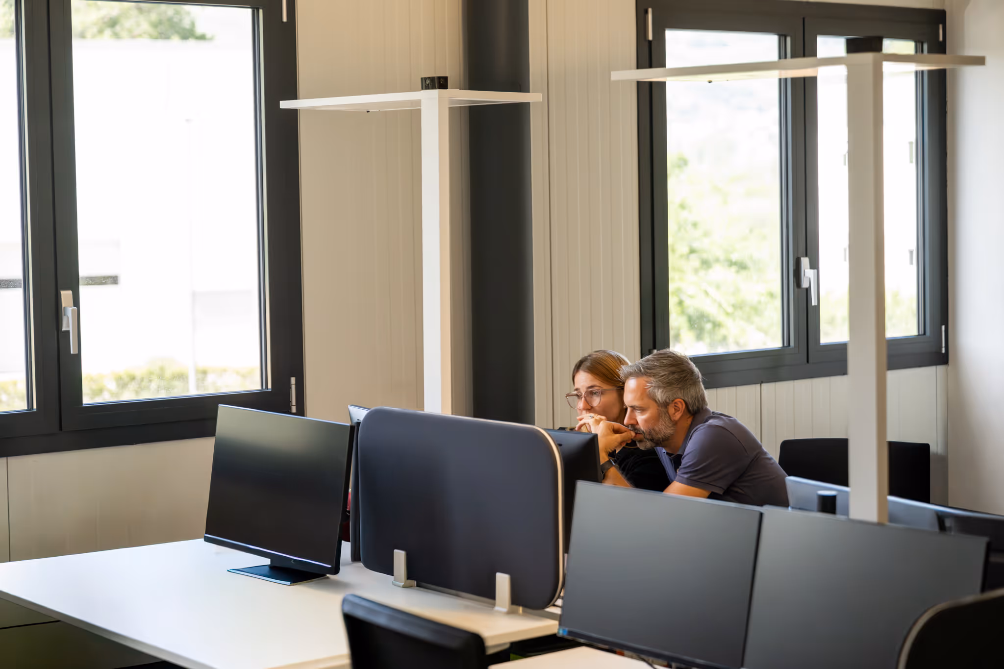 Silhouette of a person using a laptop in front of a screen displaying data charts and graphs.