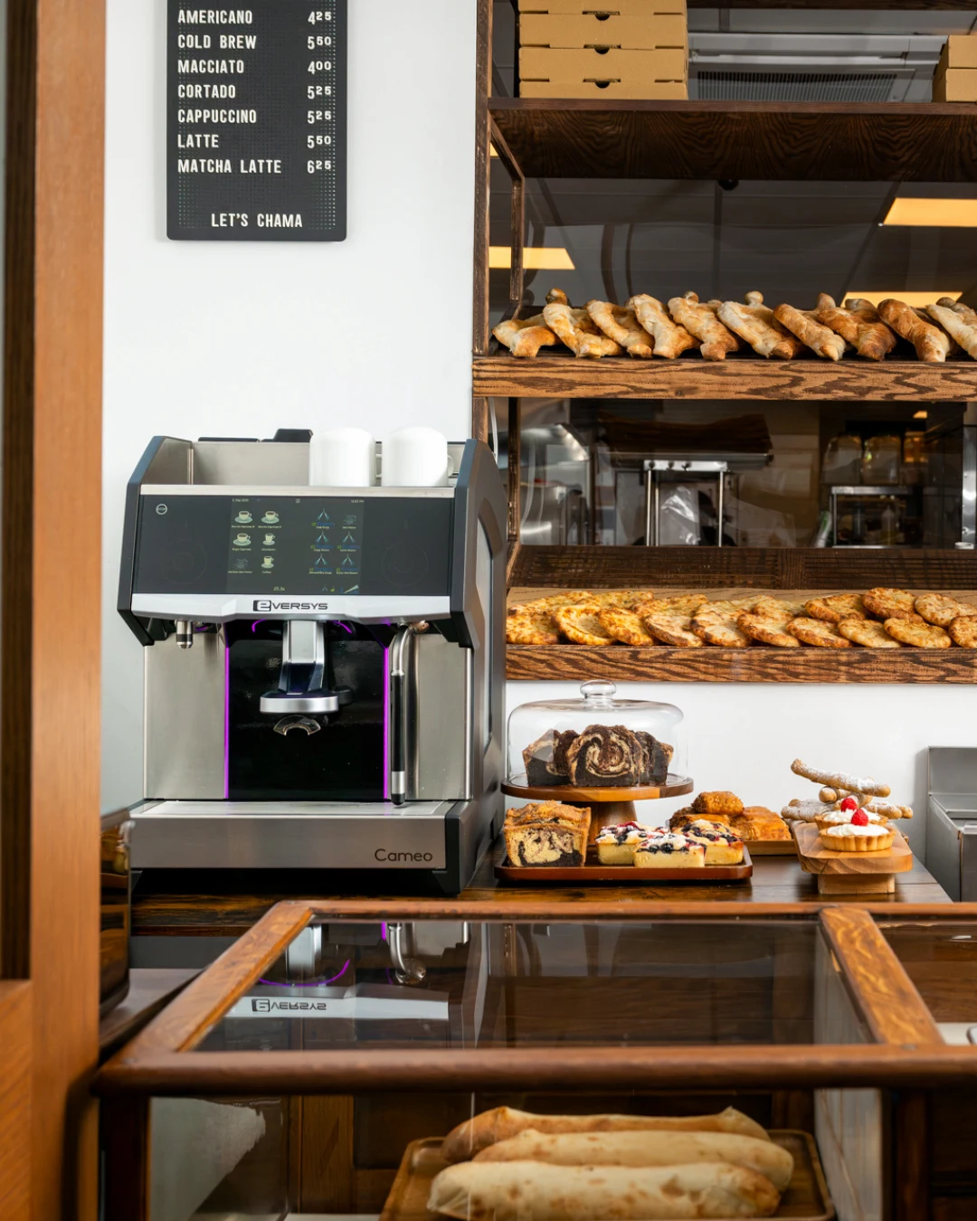 Person pouring steamed milk from a metal pitcher into a cup of espresso to create latte art.