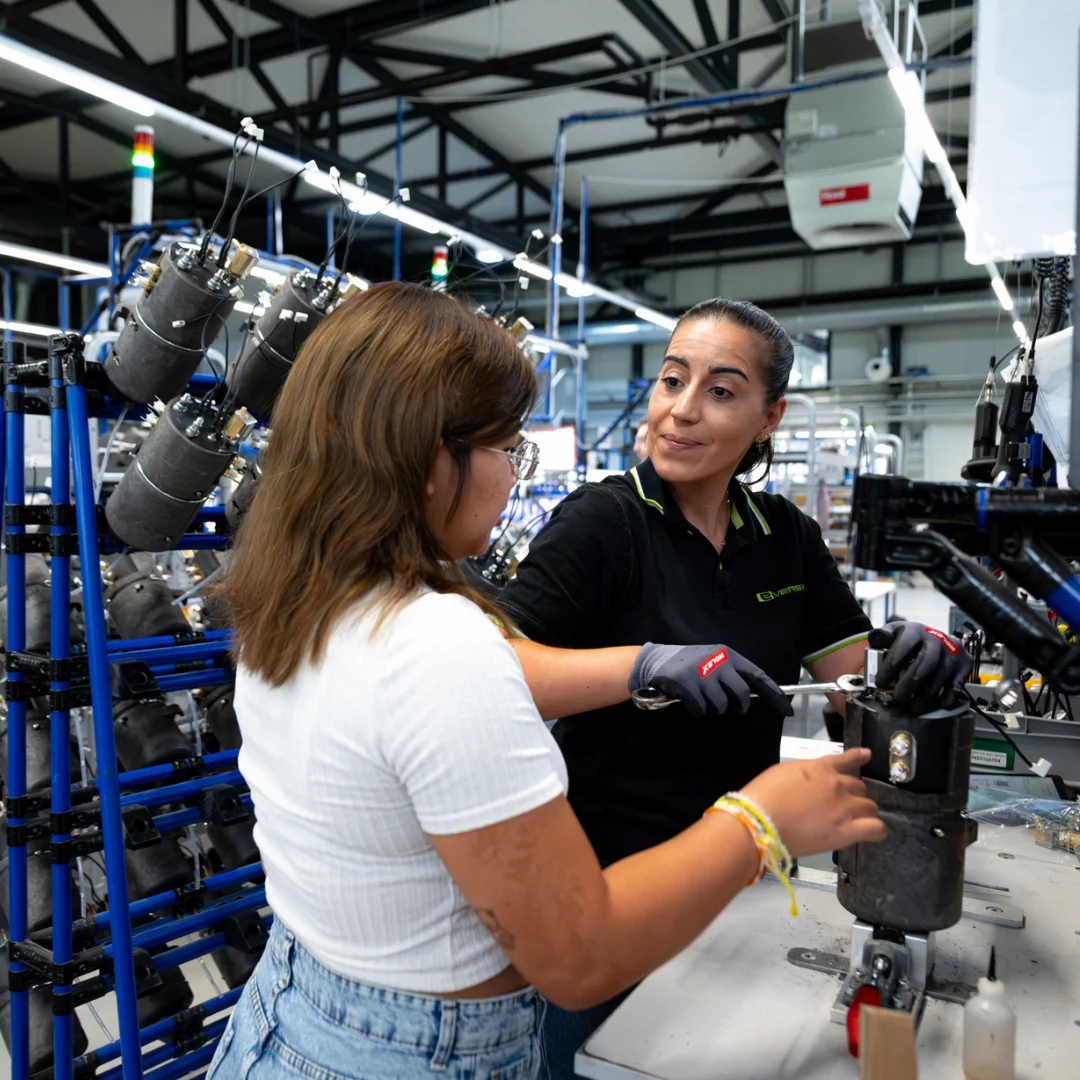 Person repairing or assembling a coffee machine with visible wires, tubes, and components.