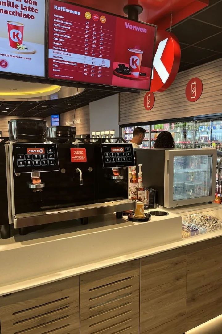 Modern coffee machine dispensing espresso into a green ceramic cup.