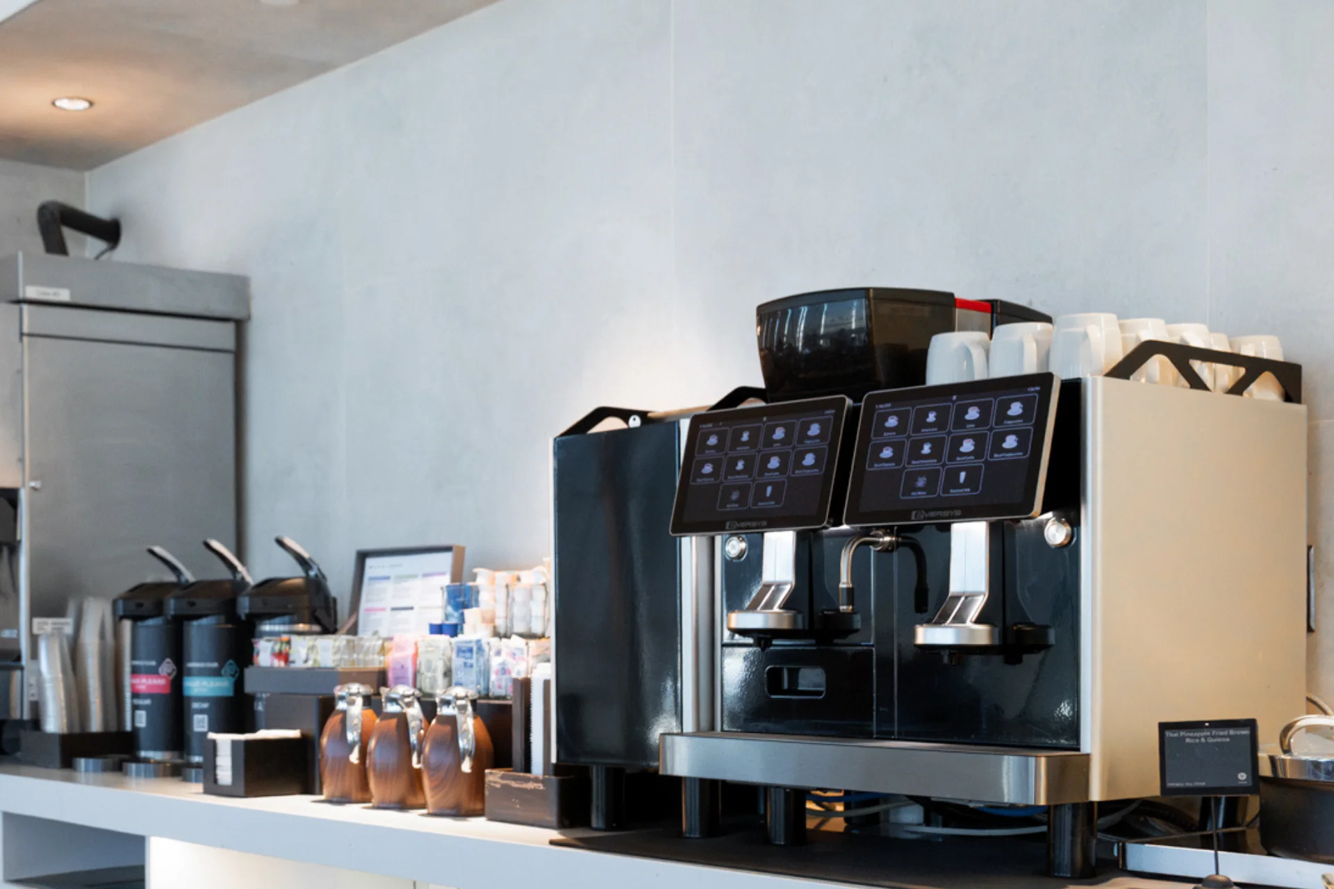Person selecting a latte option on a touchscreen of a modern coffee machine in a cafe setting.