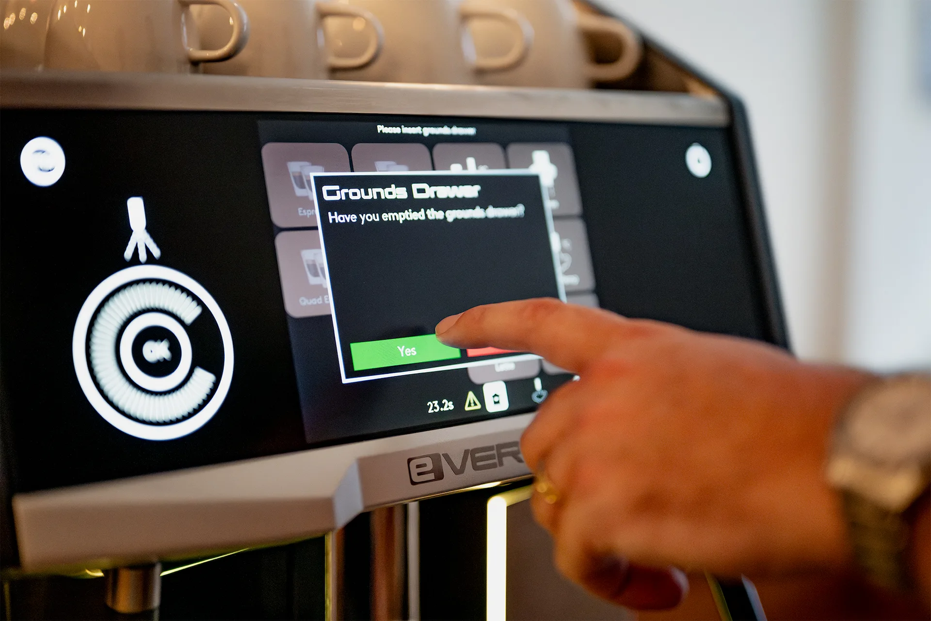 Person's finger about to press 'Yes' on a coffee machine touchscreen confirming if the grounds drawer has been emptied.