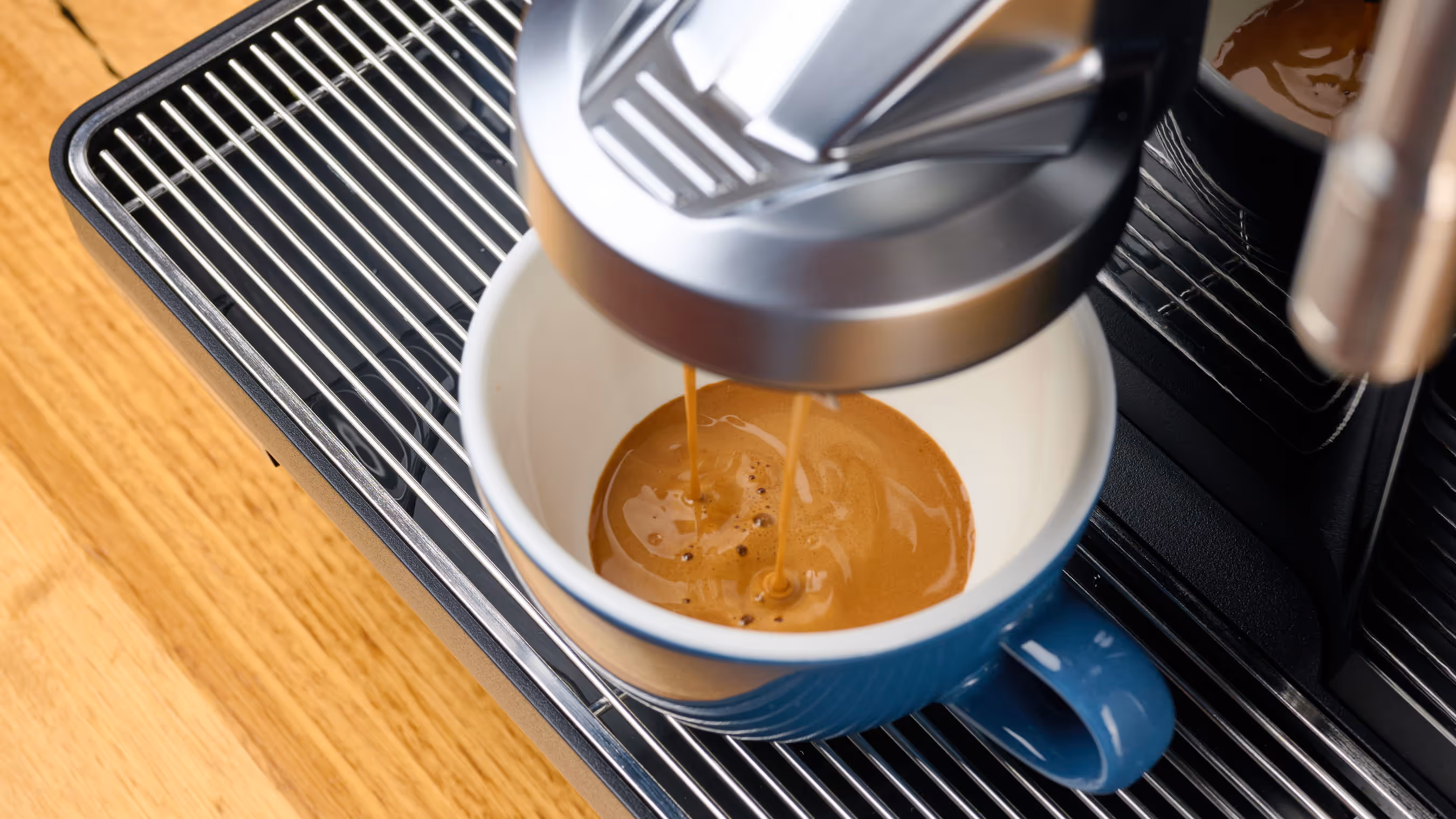 Black Eversys coffee machine on a cafe counter with menu board and pendant lights in the background.