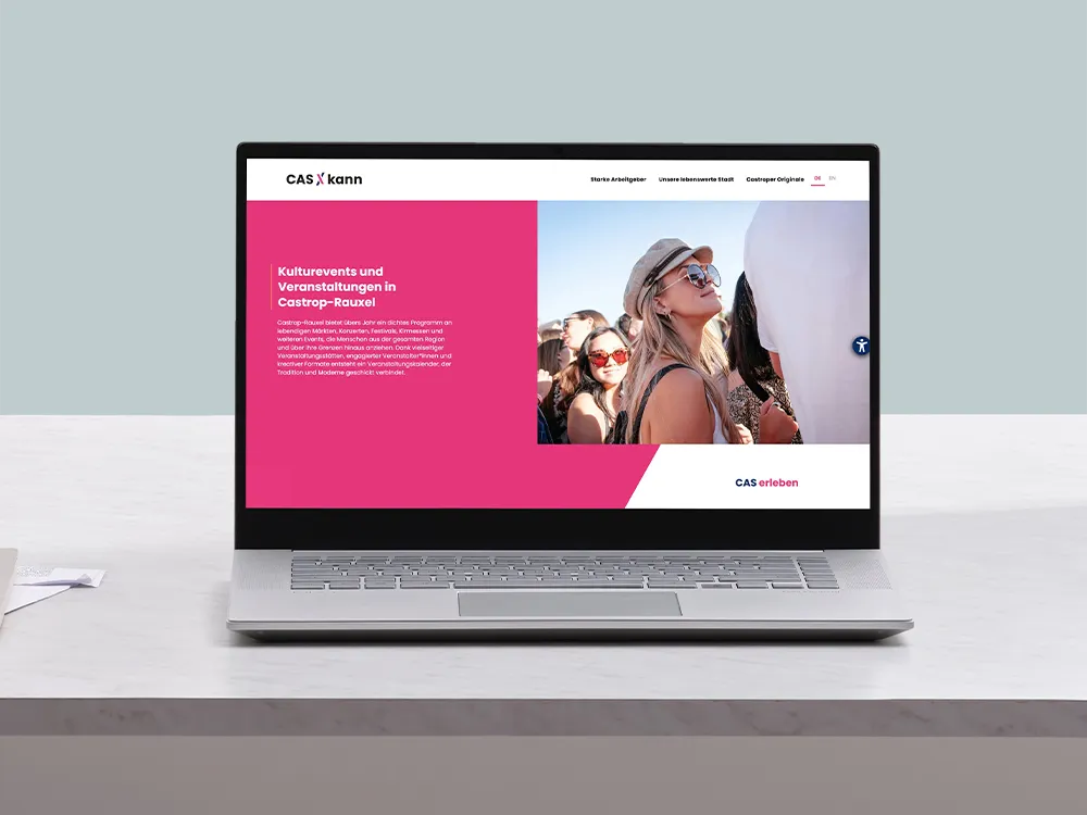 Laptop auf einem Tisch zeigt eine Webseite über Kulturveranstaltungen in Castrop-Rauxel mit Bild von Menschen auf einem Festival.