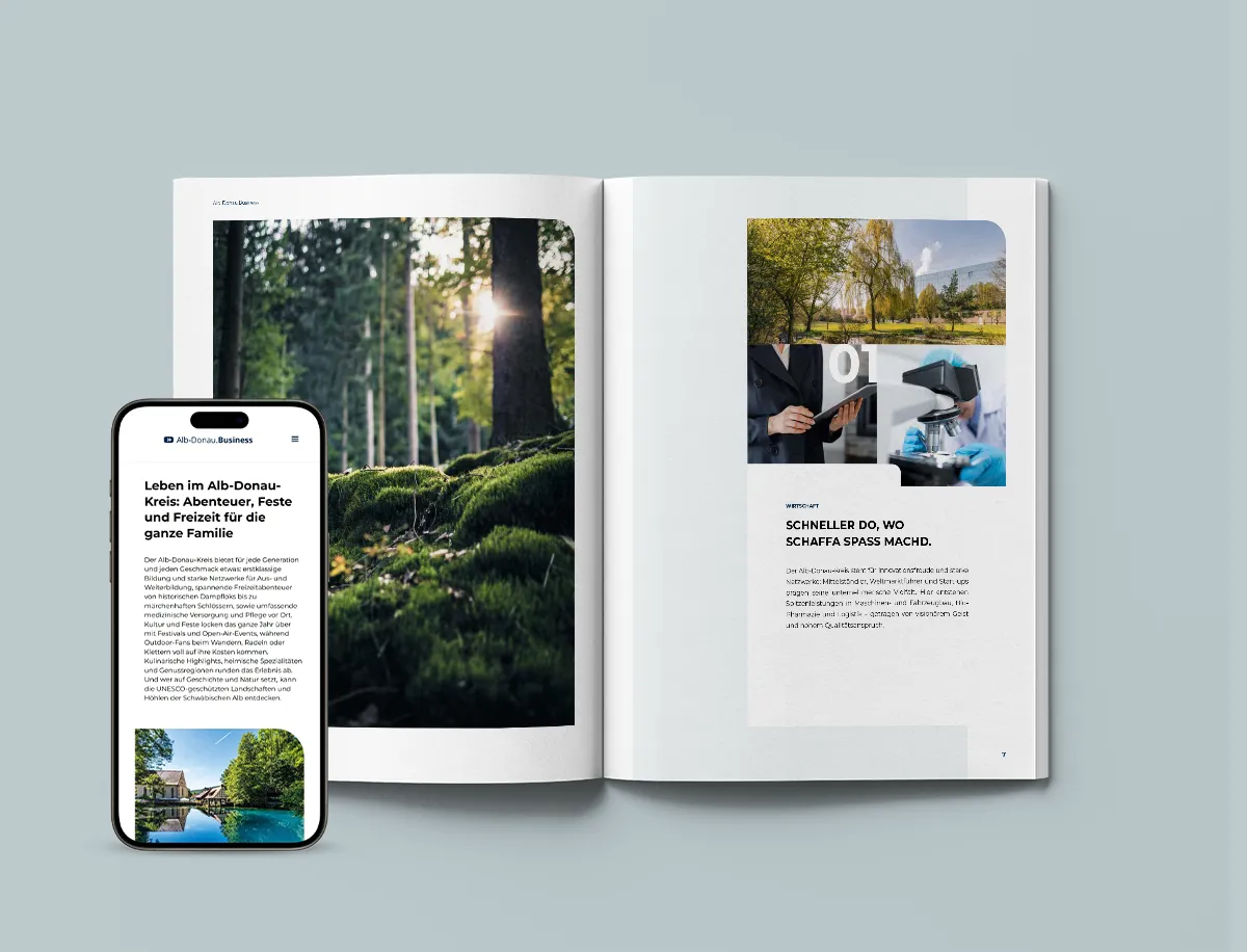 Geöffnete Broschüre mit Natur- und Geschäftsbildern neben einem Smartphone mit Webseite über Leben im Alb-Donau-Kreis.