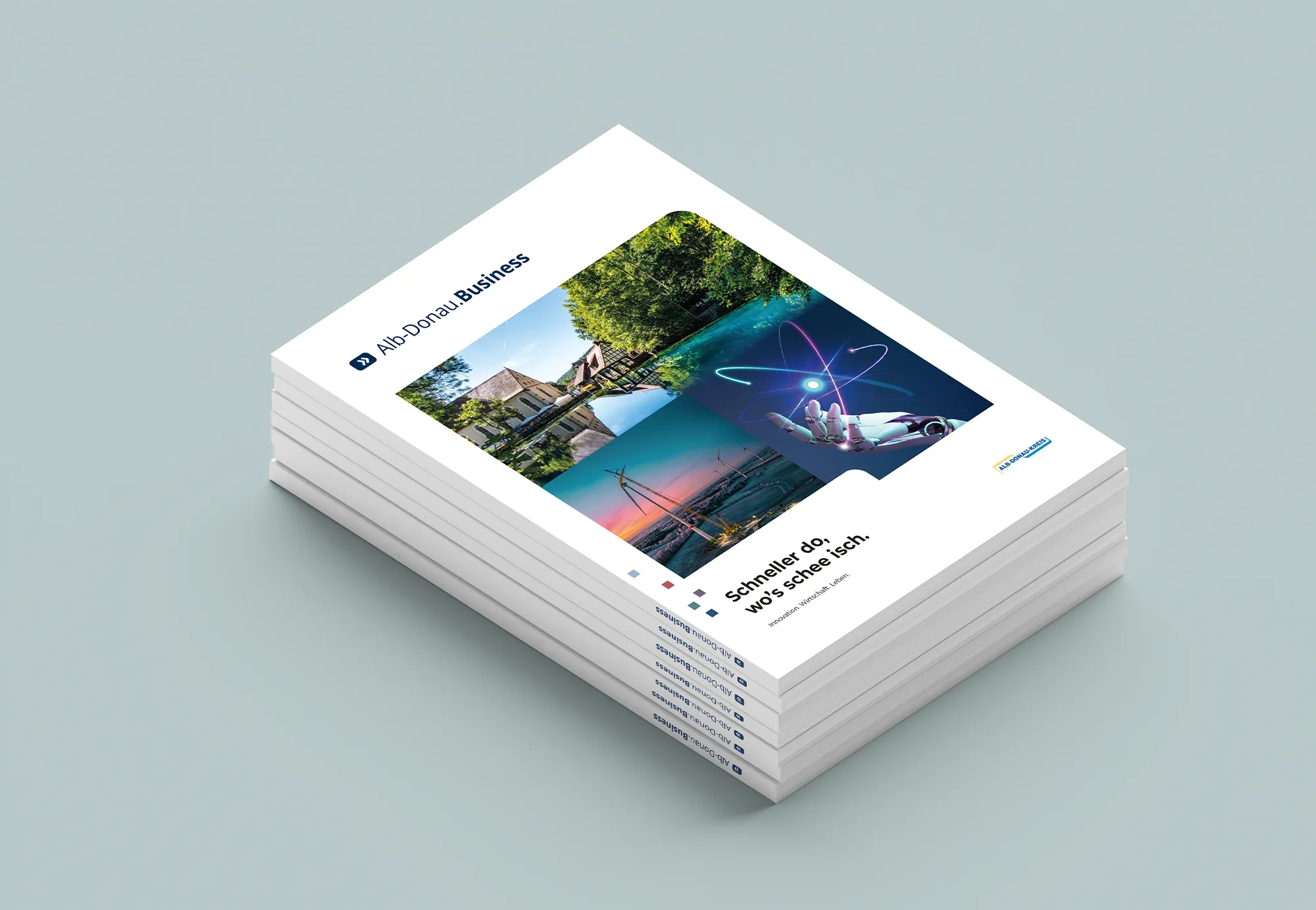 Stapel von Alb-Donau.Business Broschüren mit Bildern von Natur, Windrädern und einem Roboterarm.