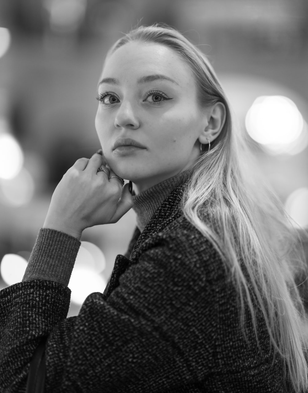 Portrait en gros plan en noir et blanc d'une jeune femme blonde regardant vers l'avant, appuyant son menton sur sa main. Artistique, réalisée pour un modèle.