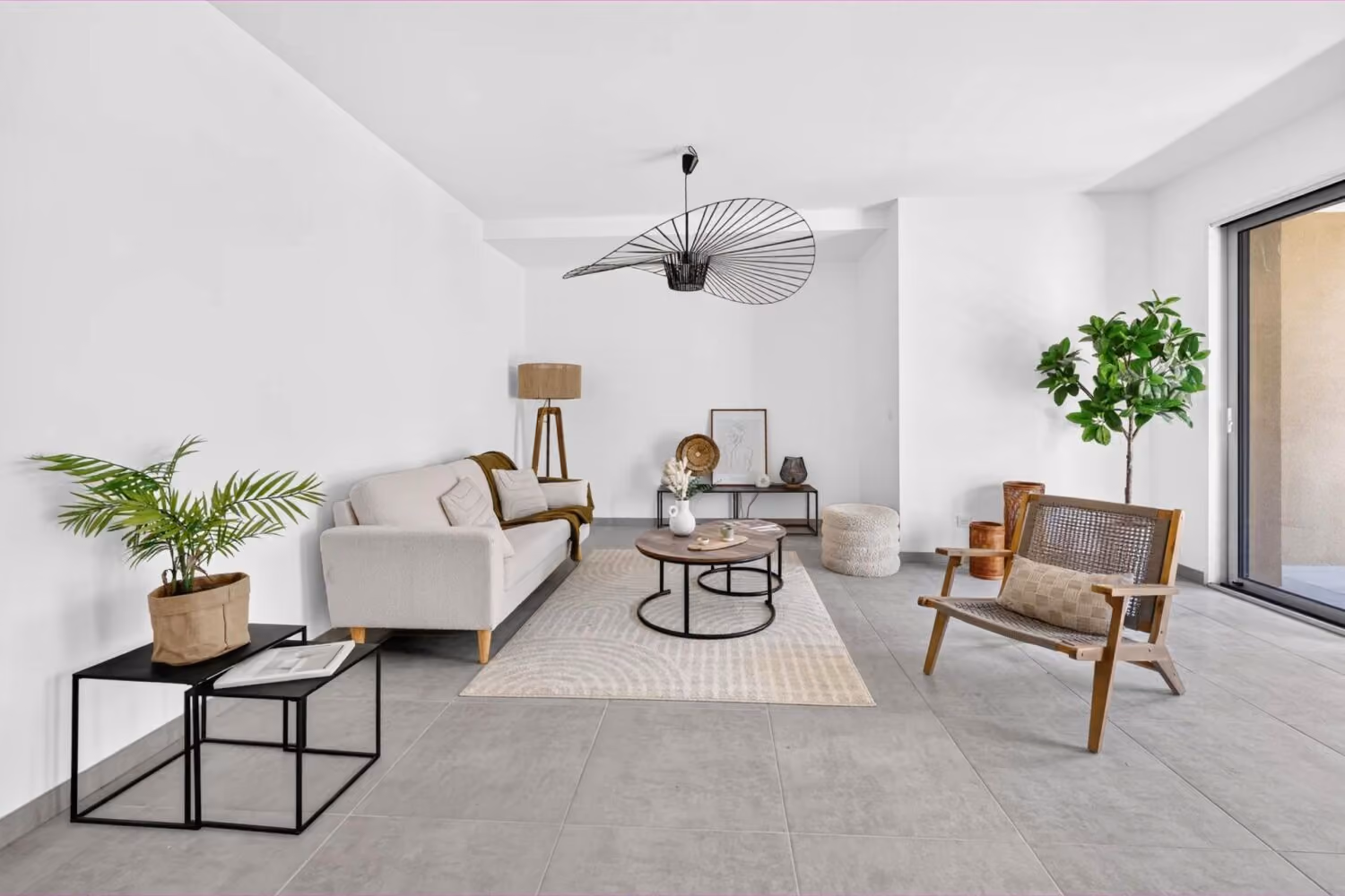 Salon moderne avec canapé beige, fauteuil en bois, tables basses rondes et plantes d'intérieur.