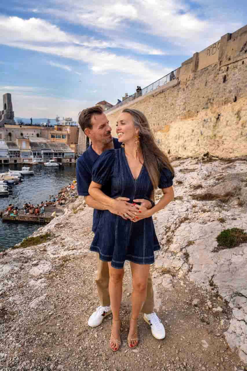 Homme souriant portant une veste noire et une chemise noire sur fond noir.